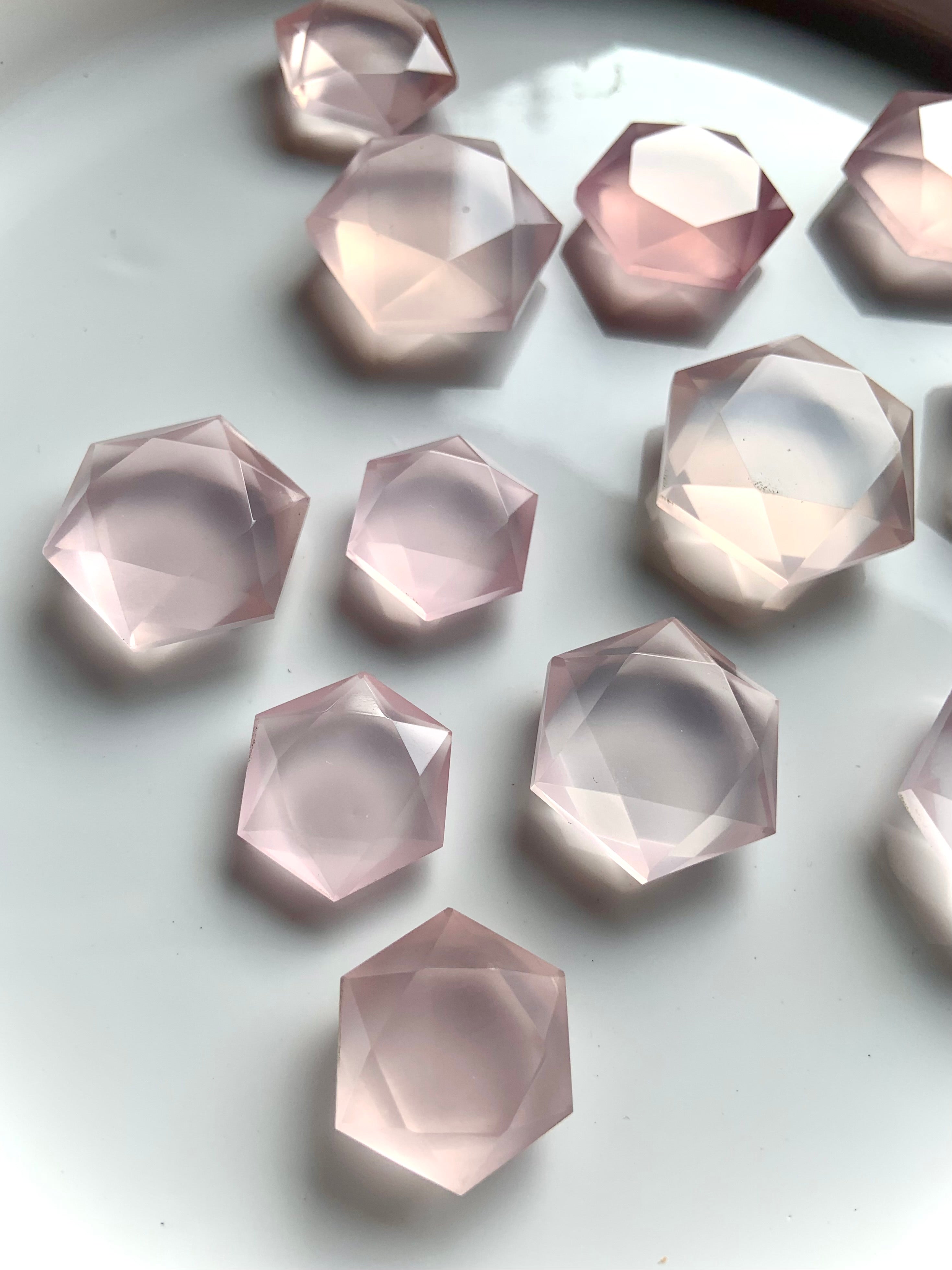 Angled closeup of faceted Rose Quartz hexagon crystals on white background, luminous pink gems for Heart Chakra love and serenity