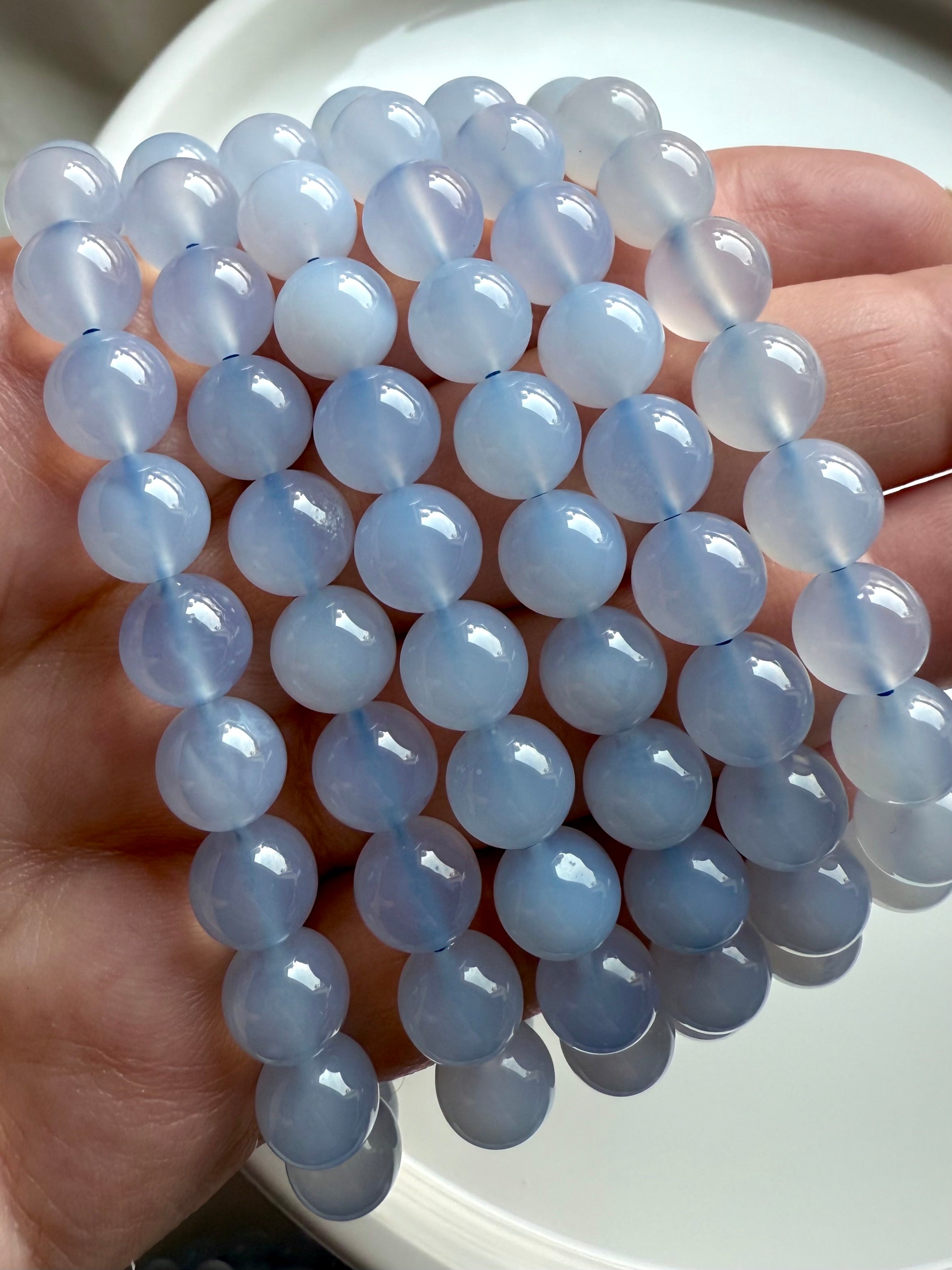 Close-up of luminous Blue Chalcedony bead bracelet in hand, showcasing soft gradients of light blue and white
