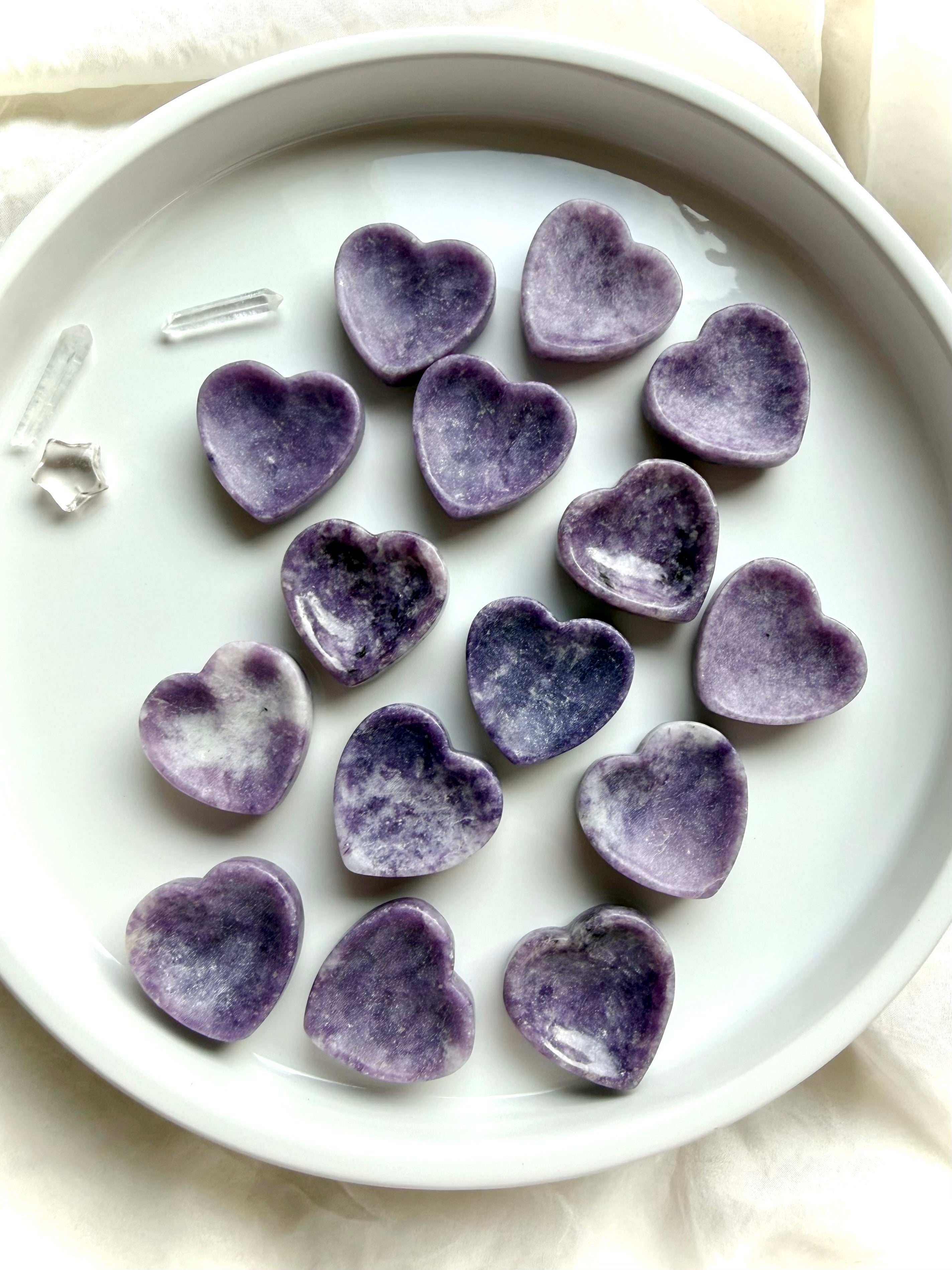 Purple Lepidolite heart bowls arranged in a dish showing petite crystal jewelry bowls and natural lavender color variation