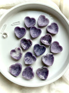 Purple Lepidolite heart bowls arranged in a dish showing petite crystal jewelry bowls and natural lavender color variation