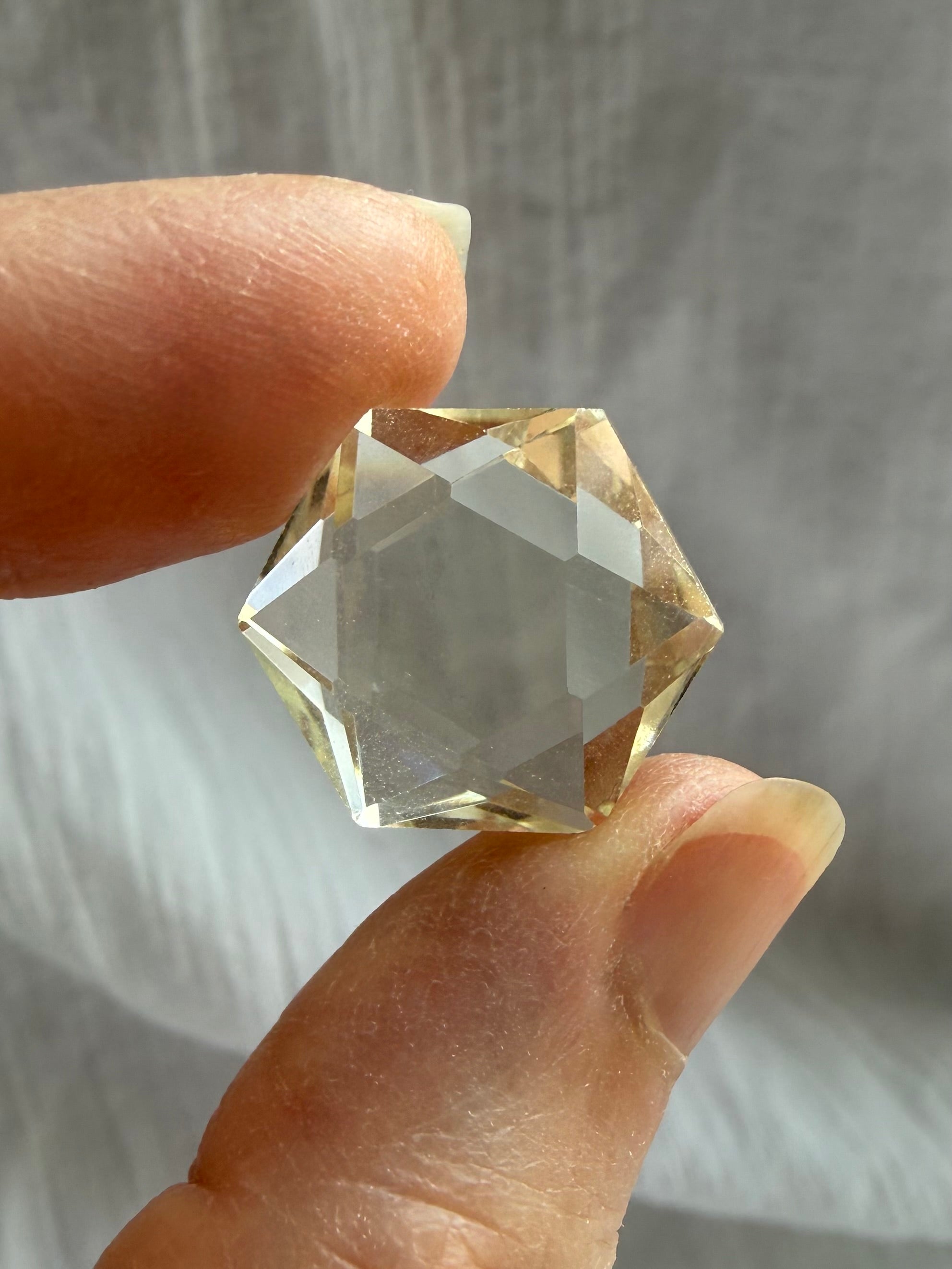 Faceted Citrine hexagon held in hand showing clear champagne-gold Quartz and precision-cut sacred geometry shape