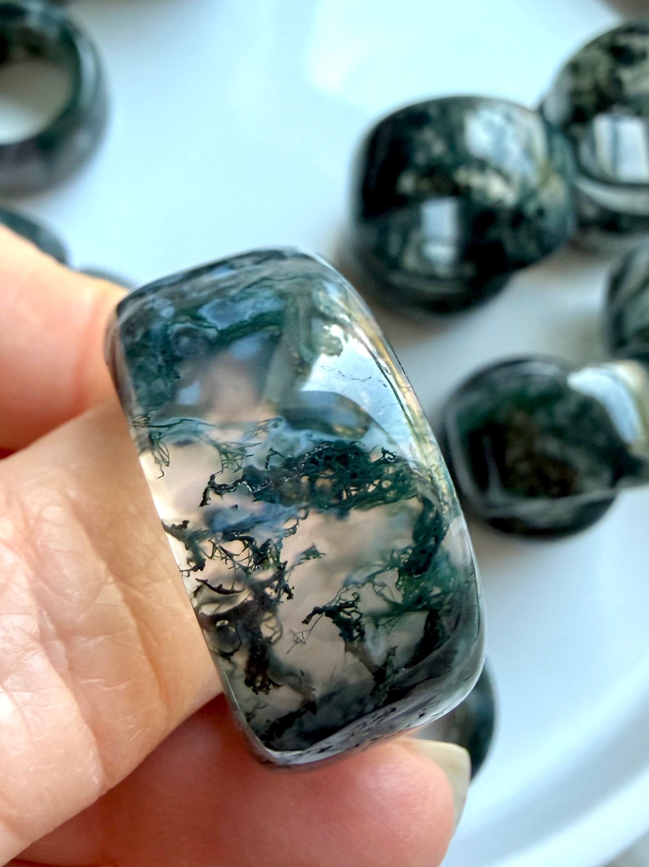 hand holding thick moss agate crystal ring closeup showing natural moss-like inclusions and earthy grounding tones