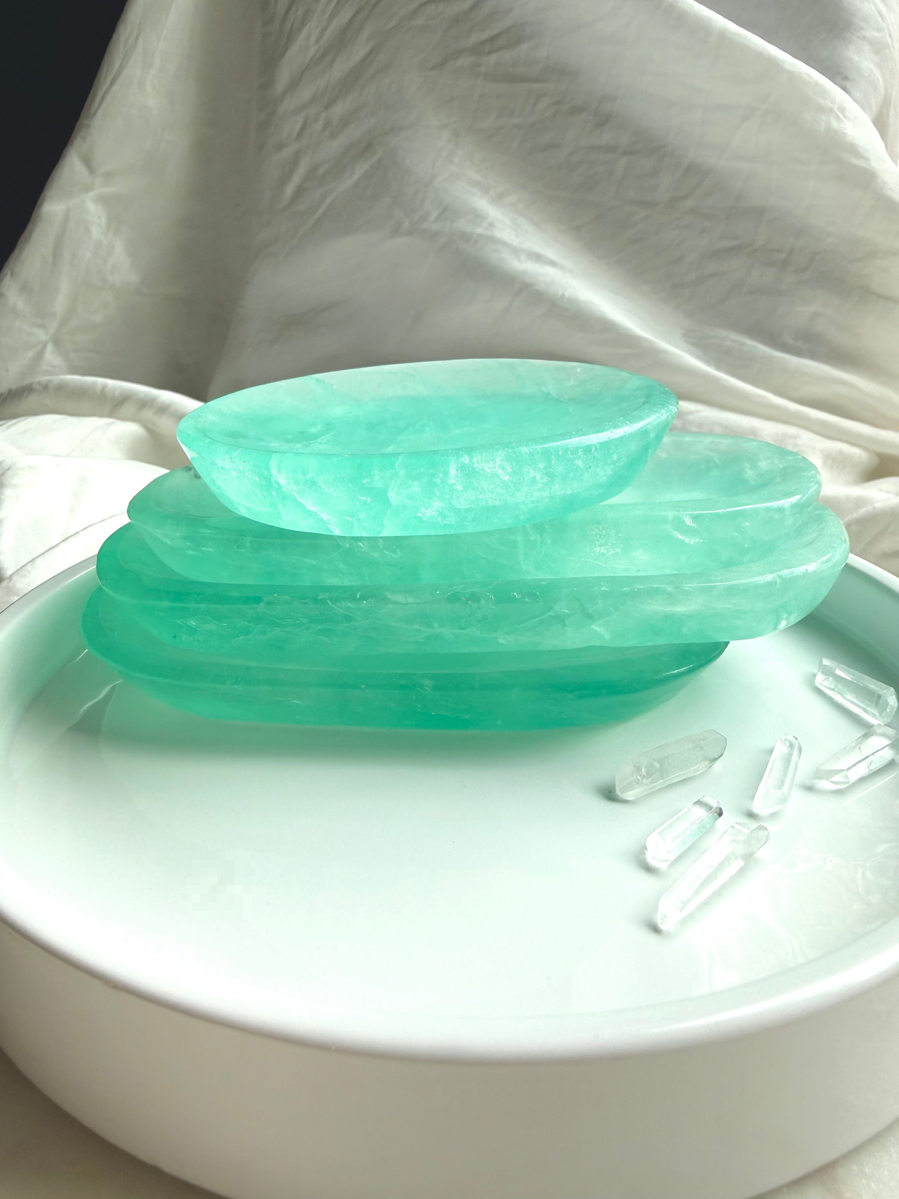 Stack of polished Green Fluorite crystal bowls showing shallow profile, saturated color, and translucent stone