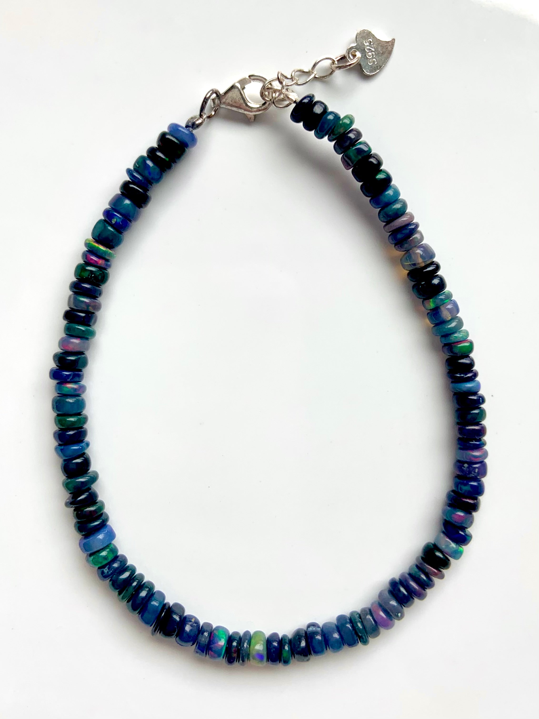 Close-up of bracelet on white background — Dainty Black Ethiopian Fire Opal bracelet with sterling silver clasp & extender — October birthstone jewelry.