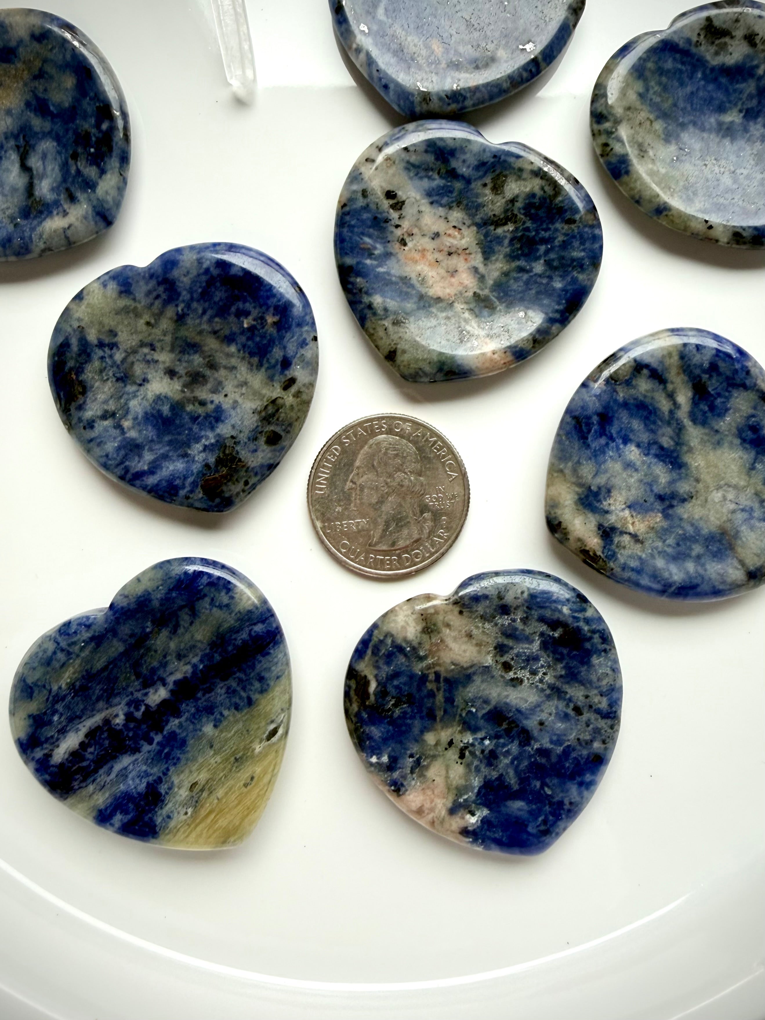 Natural sodalite heart worry stones with blue and gray mineral patterns with a US quarter for scale
