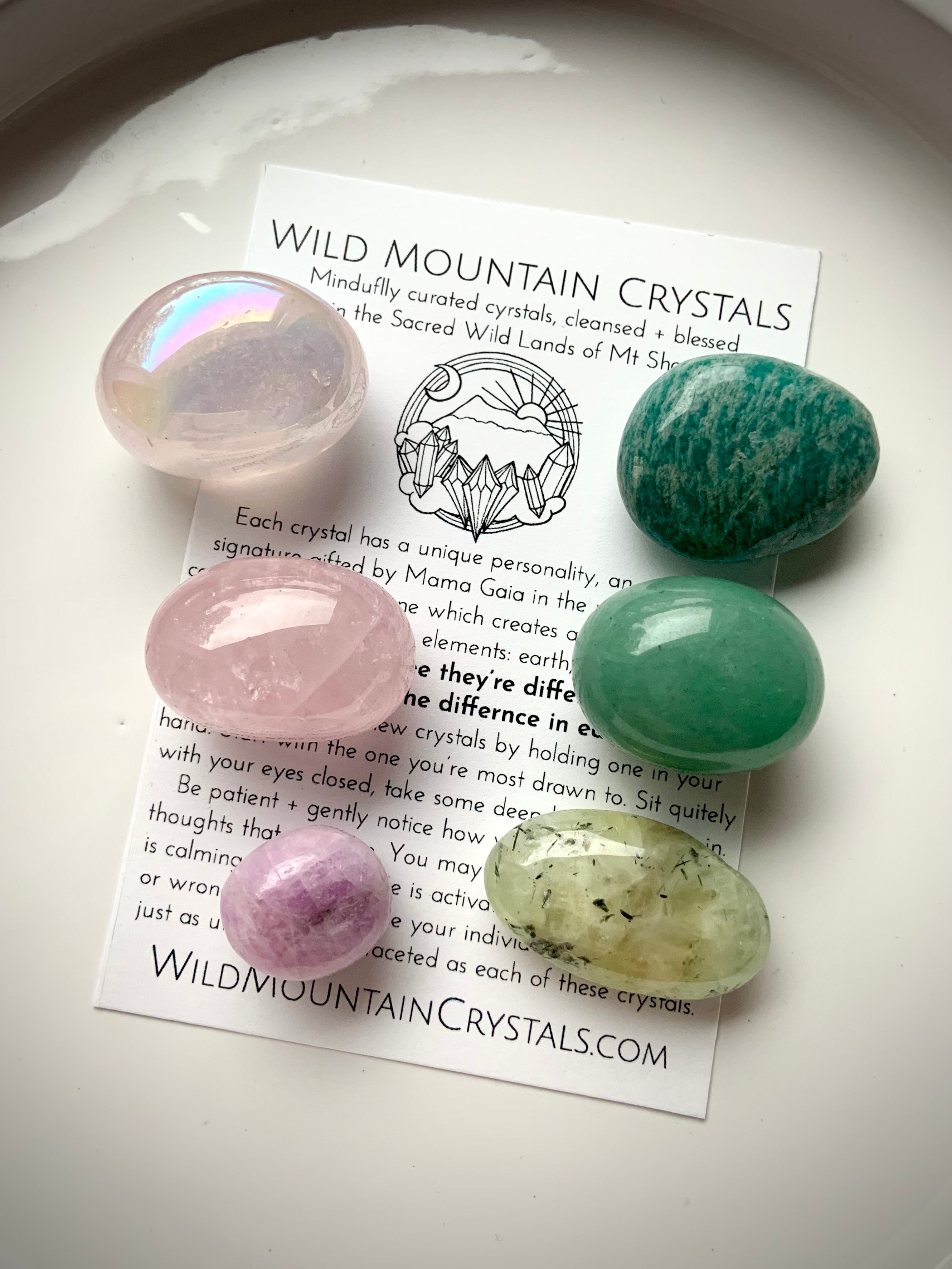Heart Chakra crystal tumble set with 6 healing stones arranged on a card — pink on the left, green on the right. Includes aura rose quartz, rose quartz, kunzite, prehnite, green aventurine, and amazonite.