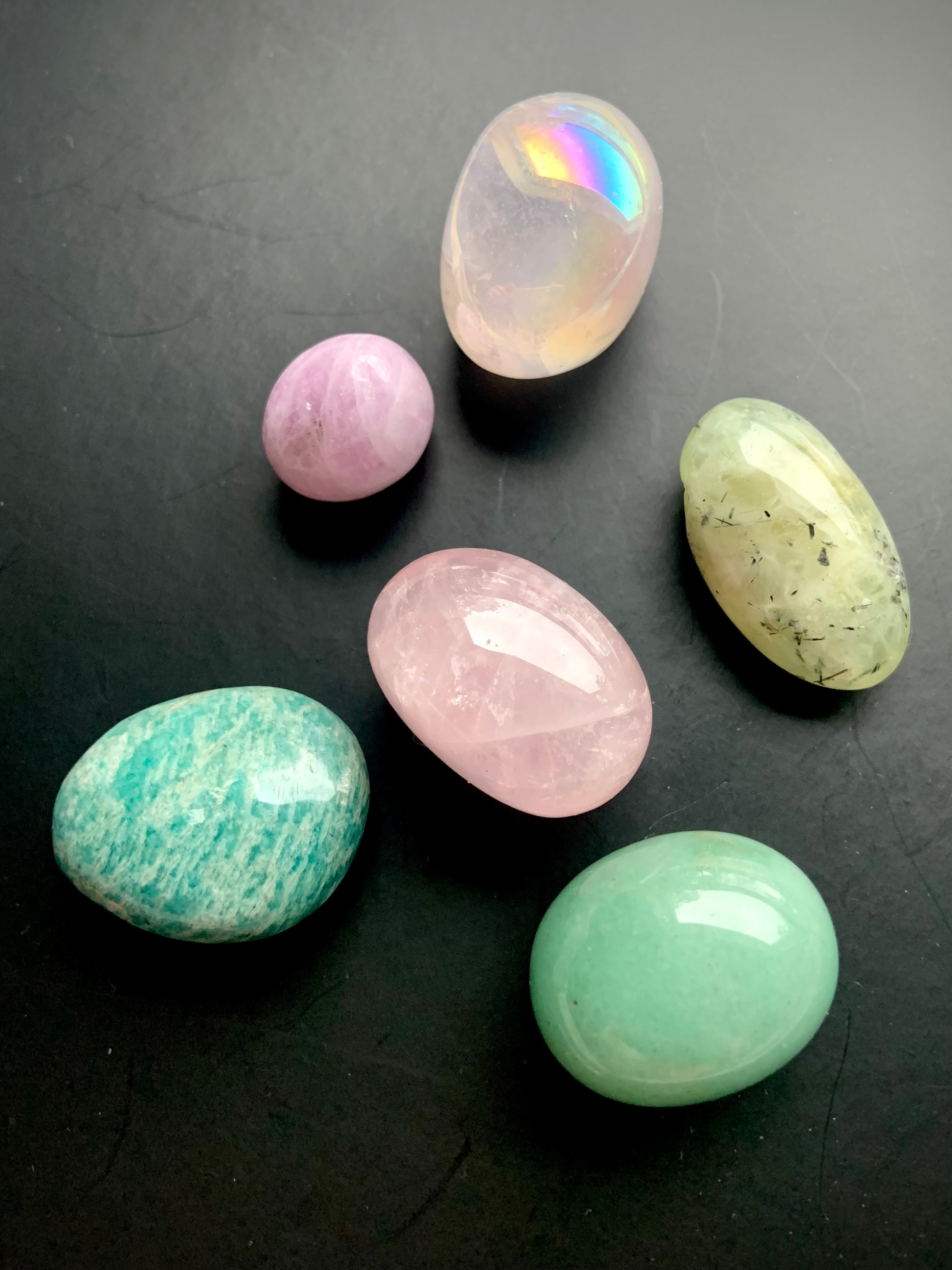 Close-up of Heart Chakra crystal set of 7 healing stones on a black background — glowing pink and green chakra stones for emotional balance and compassion.