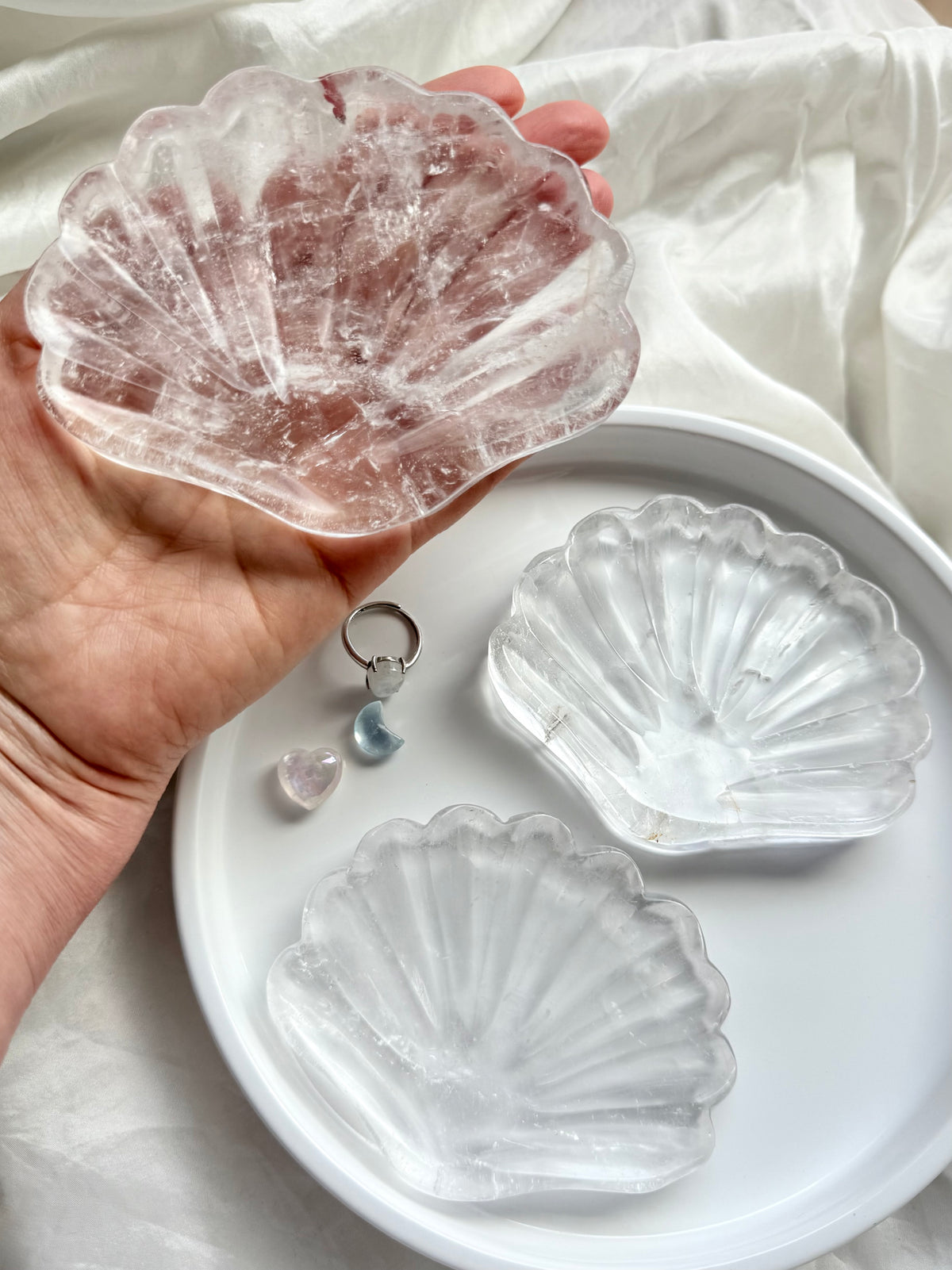 Clear Quartz shell bowls with natural translucent crystal and carved scallop details, displayed with jewelry and healing crystals