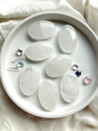Clear Quartz palm stones arranged with tiny crystals showing smooth oval shapes, white veils and luminous polished surfaces