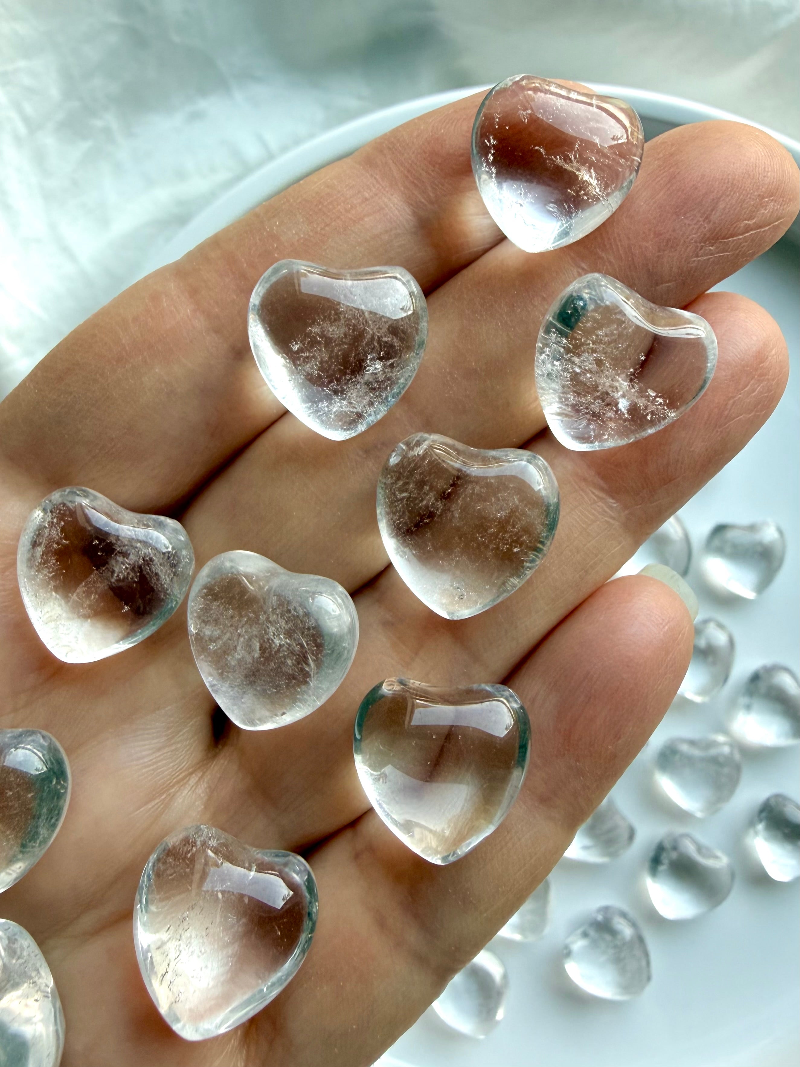 Mini Clear Quartz hearts on hand showing high clarity quartz crystal and puffy heart shape