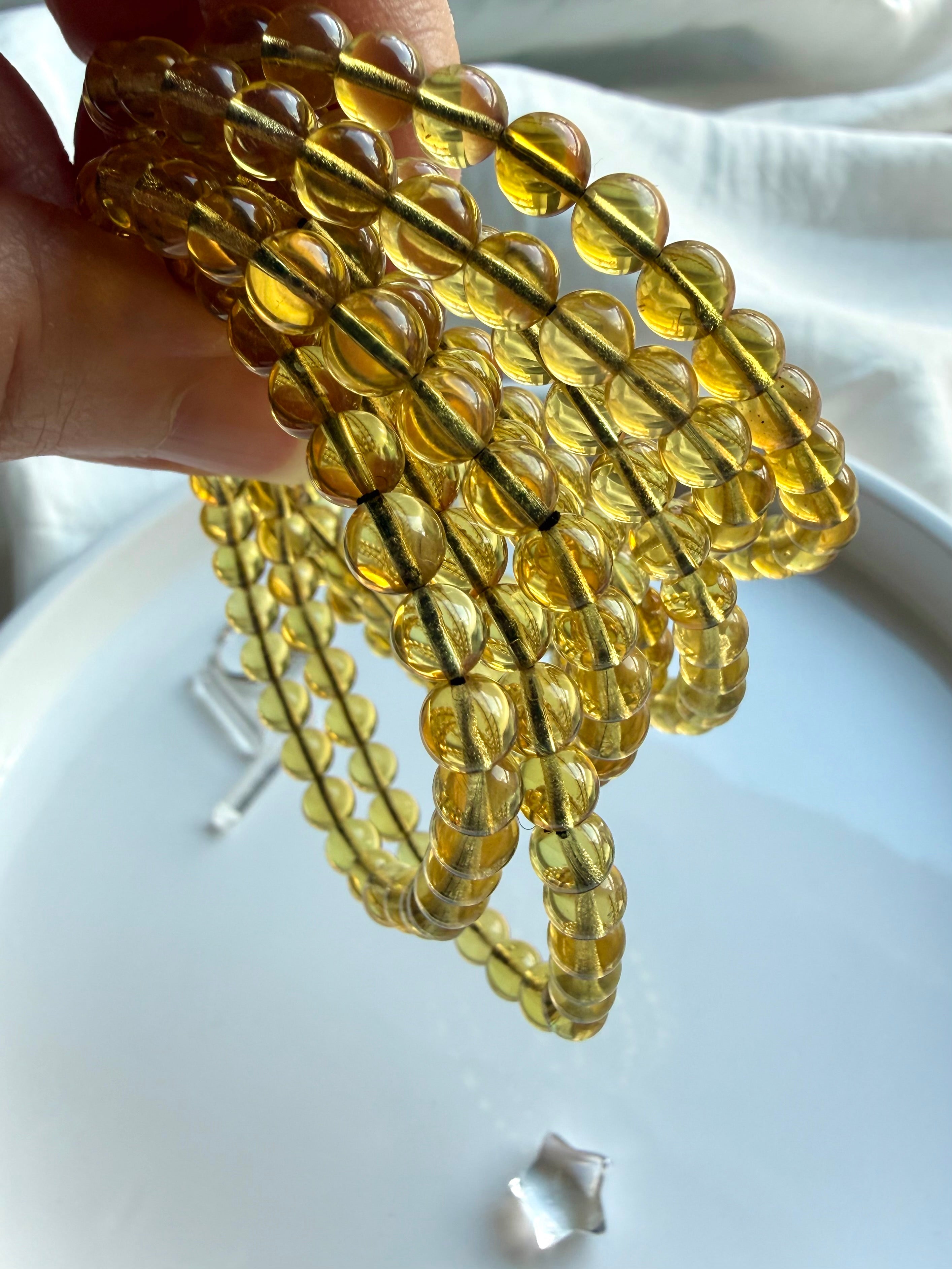 Natural Indonesian blue amber bead bracelets held to the light – golden amber crystal jewelry