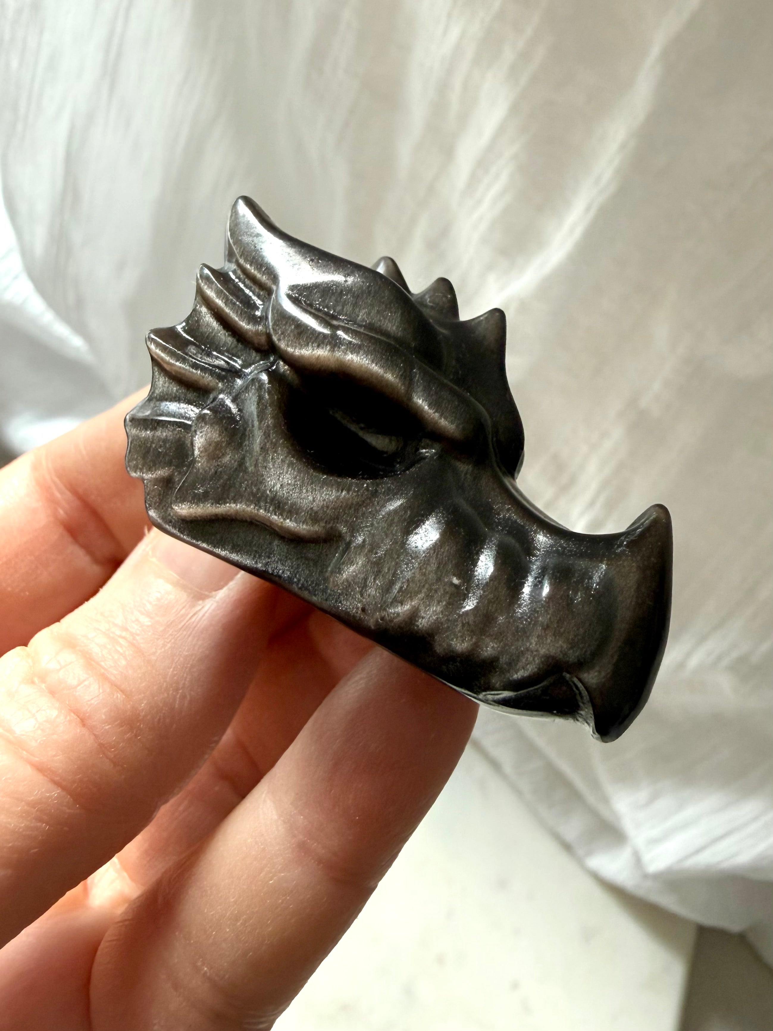 angled view of silver sheen obsidian dragon carving showing sculpted details and high-gloss finish, grounding crystal for shadow integration