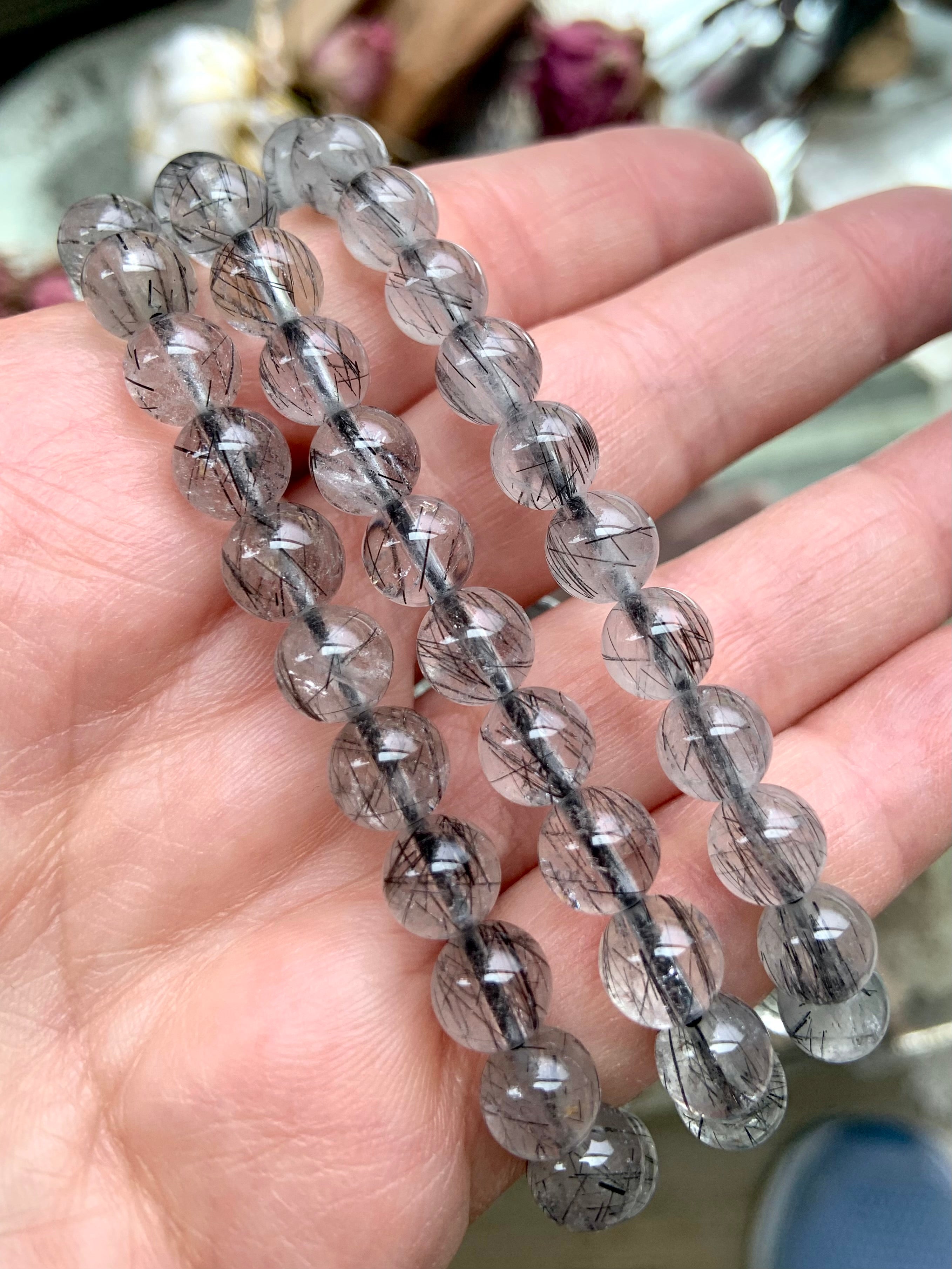 Three high-quality Black Tourmaline in Quartz bracelets displayed on a hand, highlighting the clarity and delicate needle-like black tourmaline strands