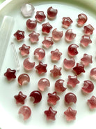 Assortment of mini Strawberry Quartz stars and crescent moons in varying shades of pink and red for love, joy and crystal rituals