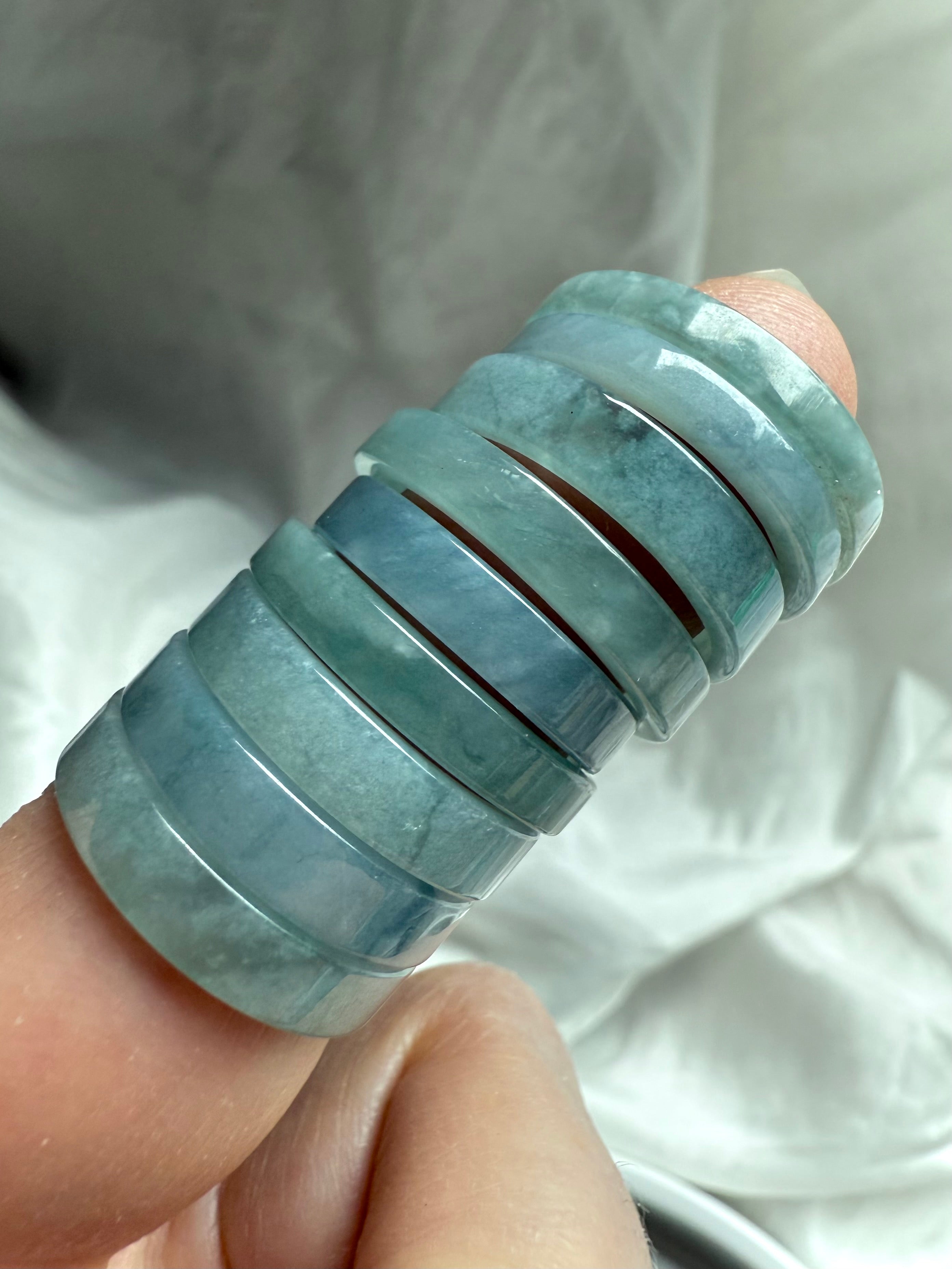 Close-up of flat Blue Water Jade rings stacked on finger, showing natural variation in tone