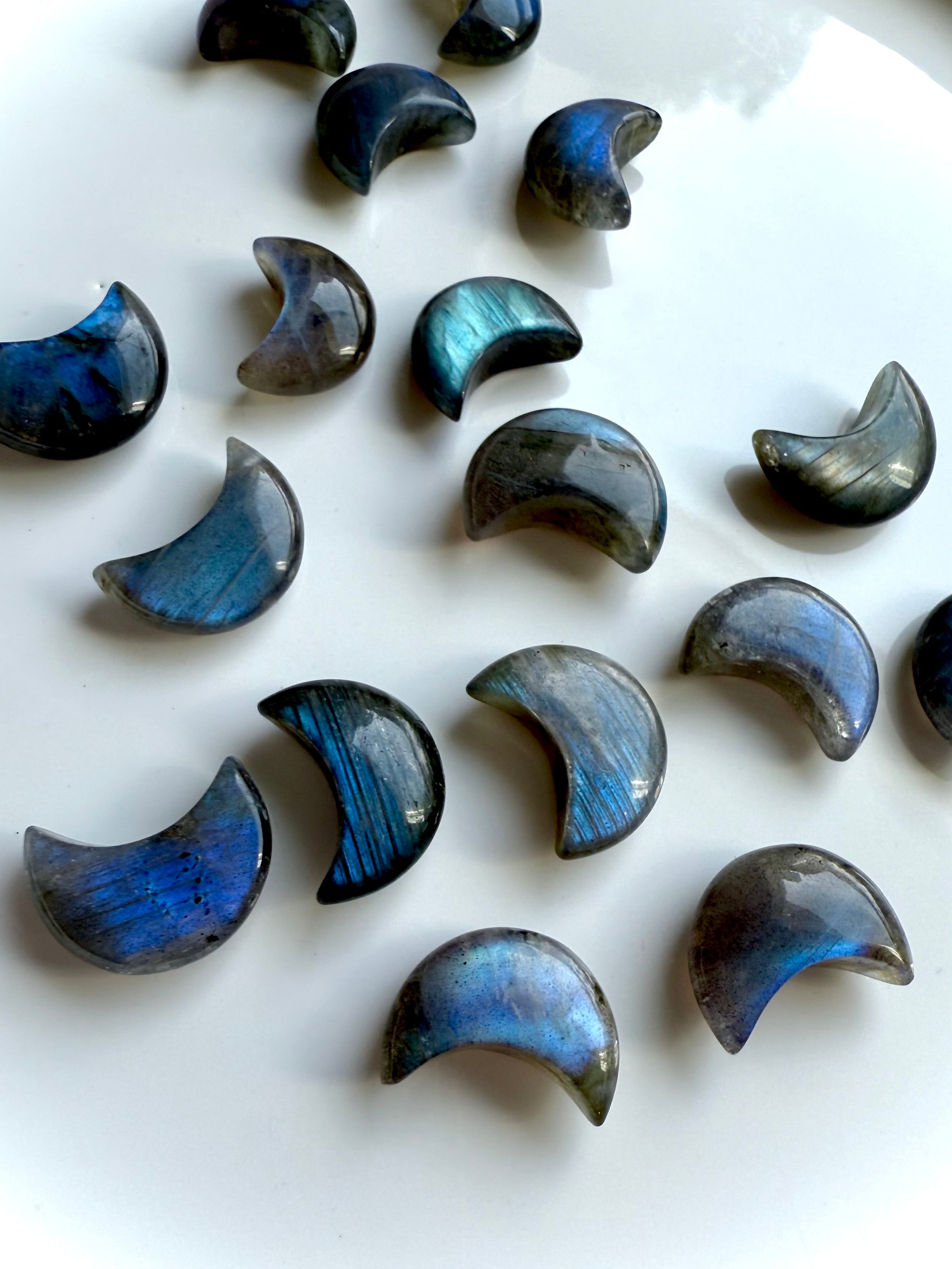 Angled view of deep blue Labradorite crescent moon crystals on a white background — mini moons for chakra work & intuitive energy healing.
