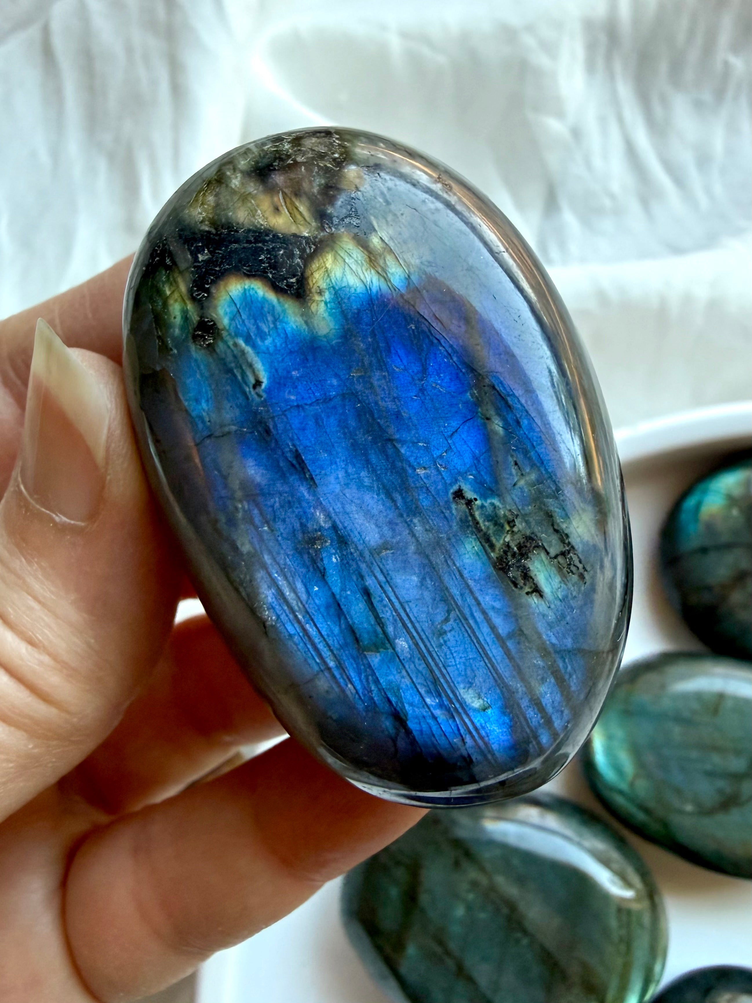 Blue flash Labradorite palm stone held in hand showing vibrant iridescence and natural polished finish