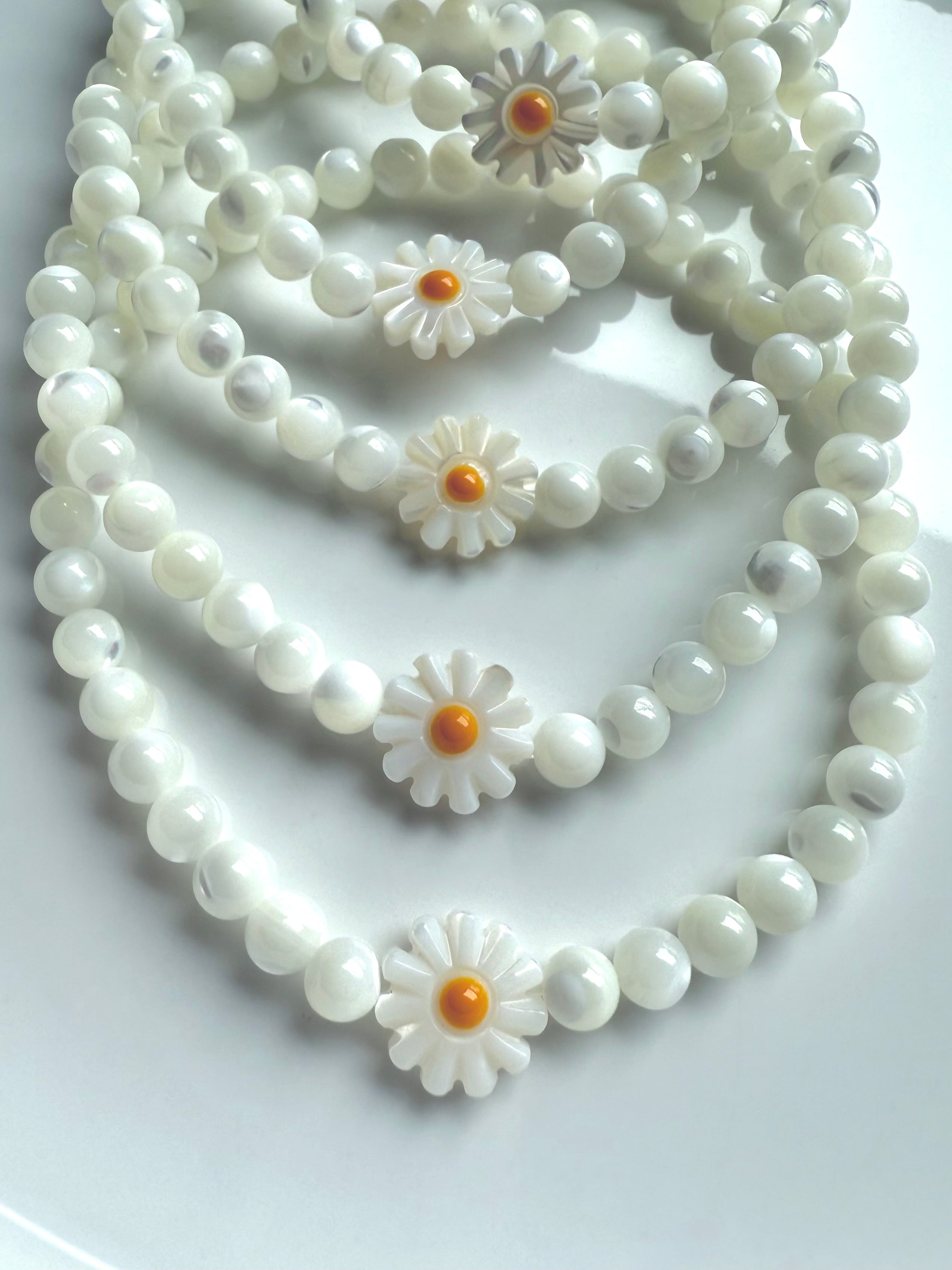 Close-up of daisy bead design on Mother of Pearl bracelet, showcasing glowing shell beads and carved flower detail