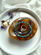 Golden Healer Quartz bowl as a crystal jewelry dish holding bracelets and a ring, styled with flowers and altar crystals on white plate