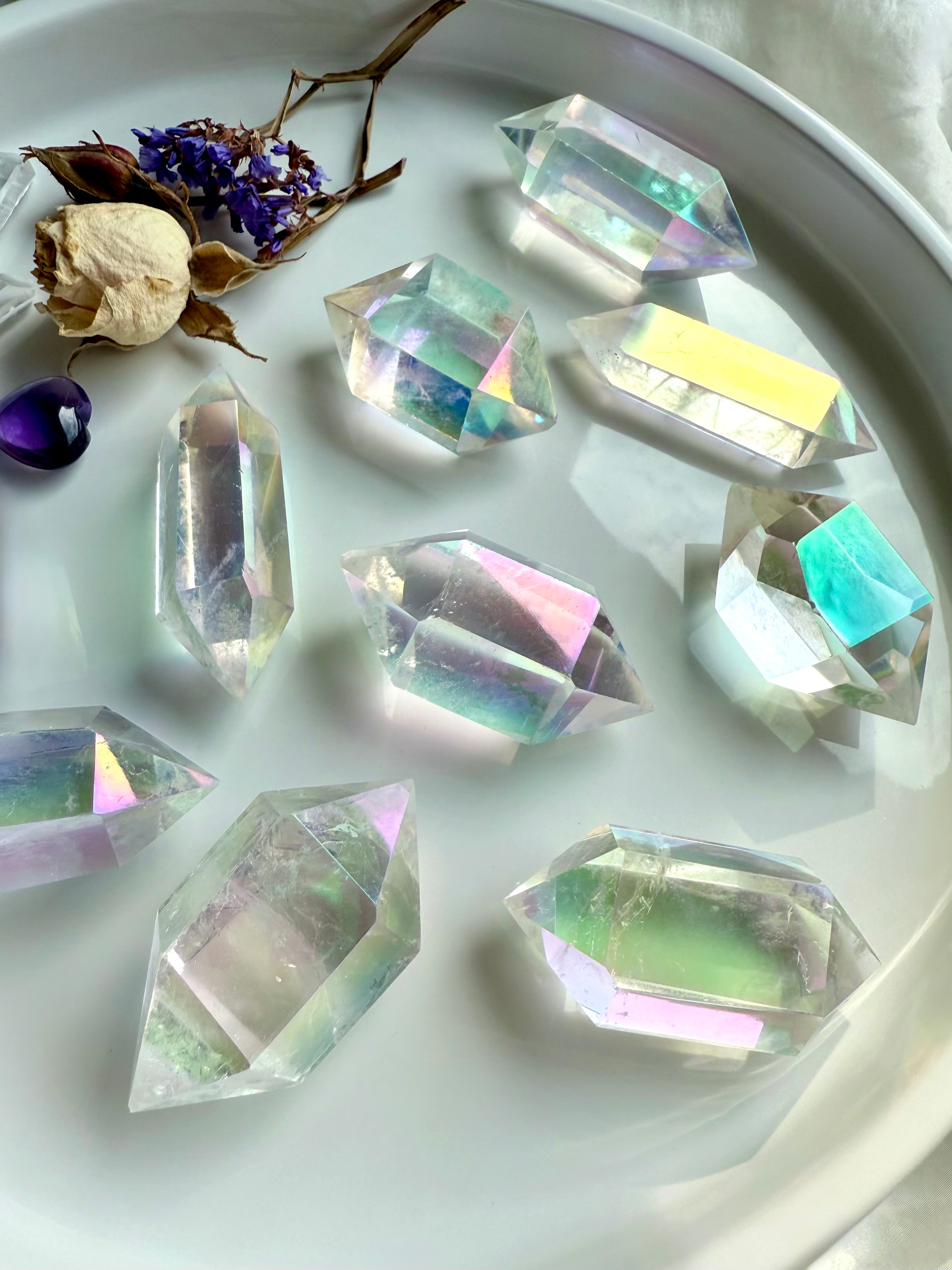 Collection of Angel Aura Quartz double terminated points arranged in a round dish with dried flowers and amethyst accent