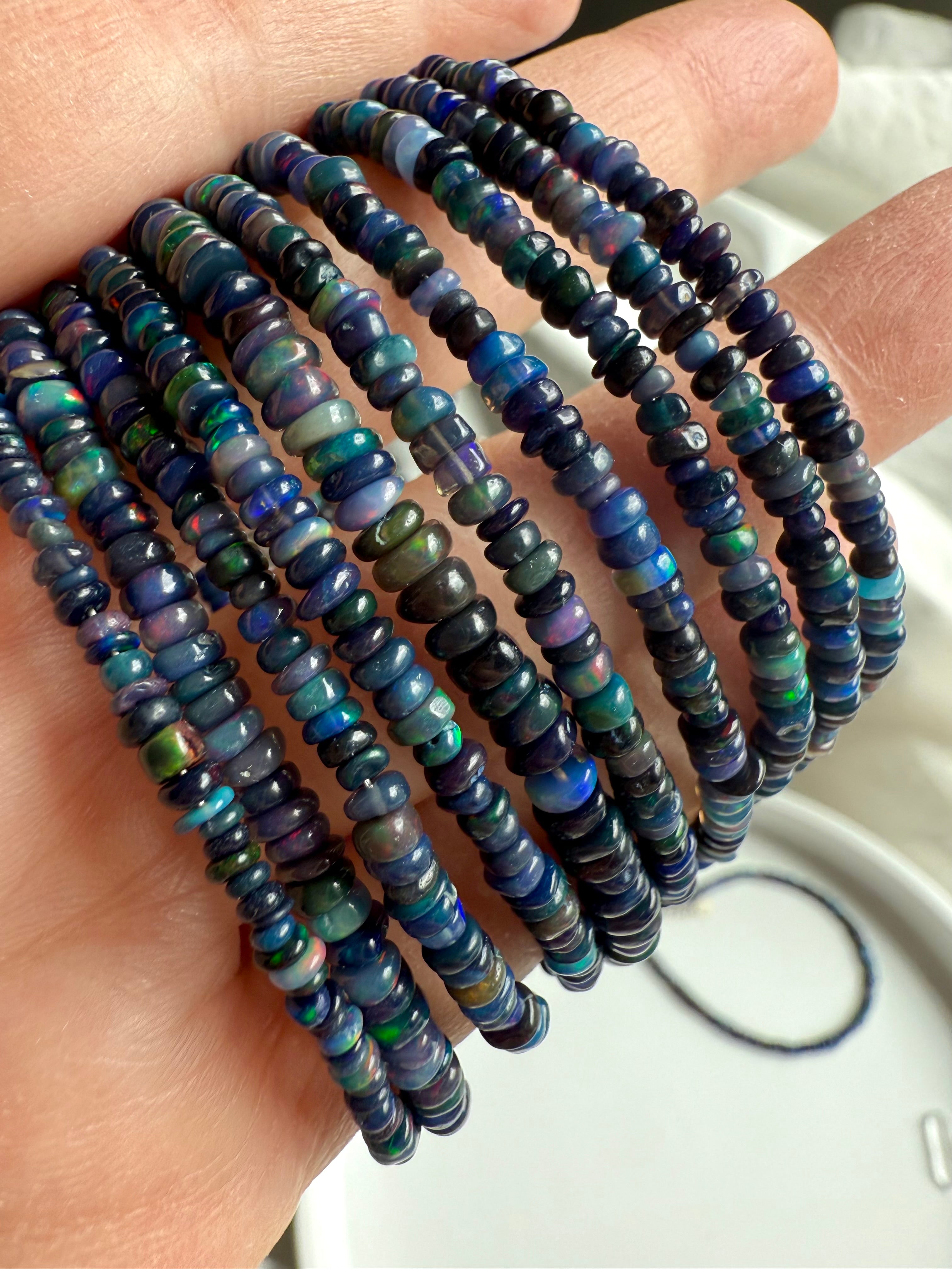 Detail shot showing rainbow flash — Close-up of luminous Black Fire Opal beads with sterling silver clasp — real opal jewelry.