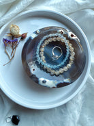 Orca Agate offering bowl displayed with gemstone bracelets and ring, styled as an altar dish for sacred jewelry