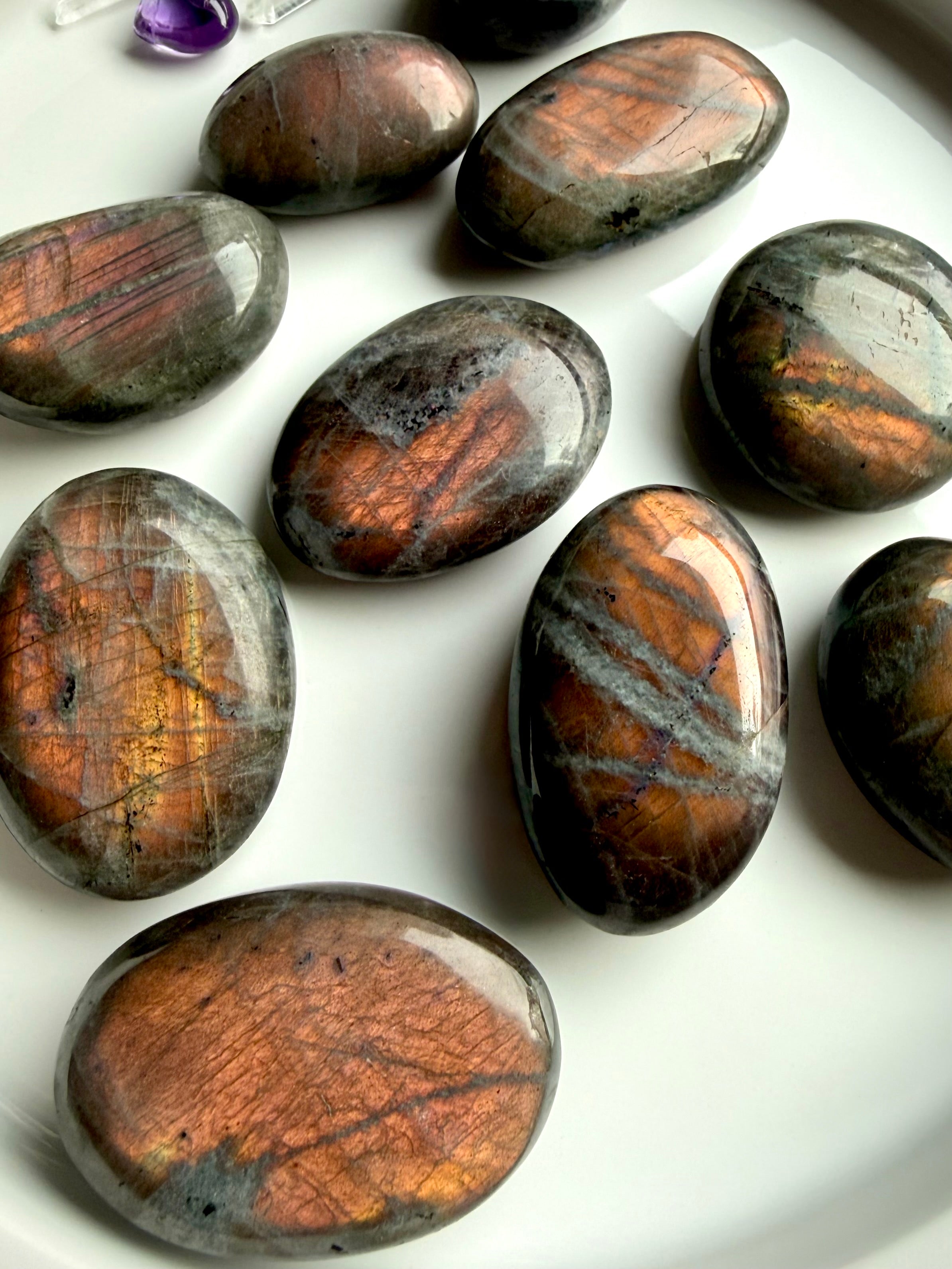 Peach Sunset Labradorite palm stones with glowing orange and peach flash on white tray