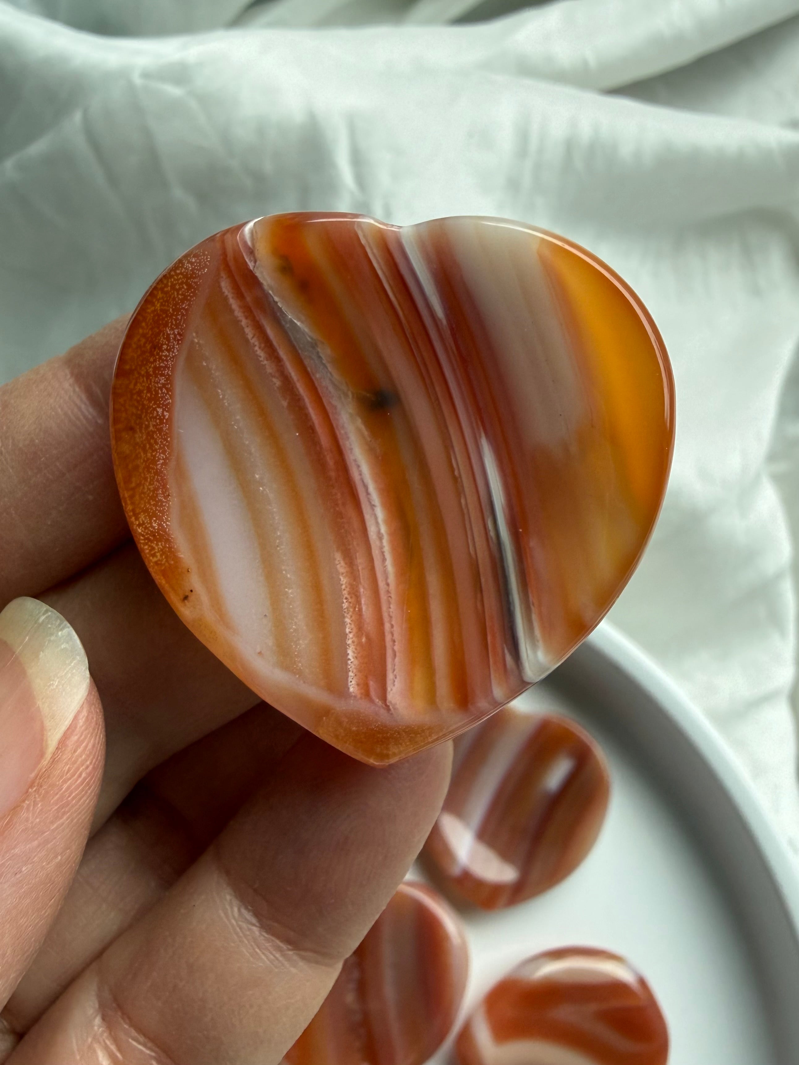 Carnelian heart worry stone crystal thumb stone held in hand for Root and Sacral Chakra grounding