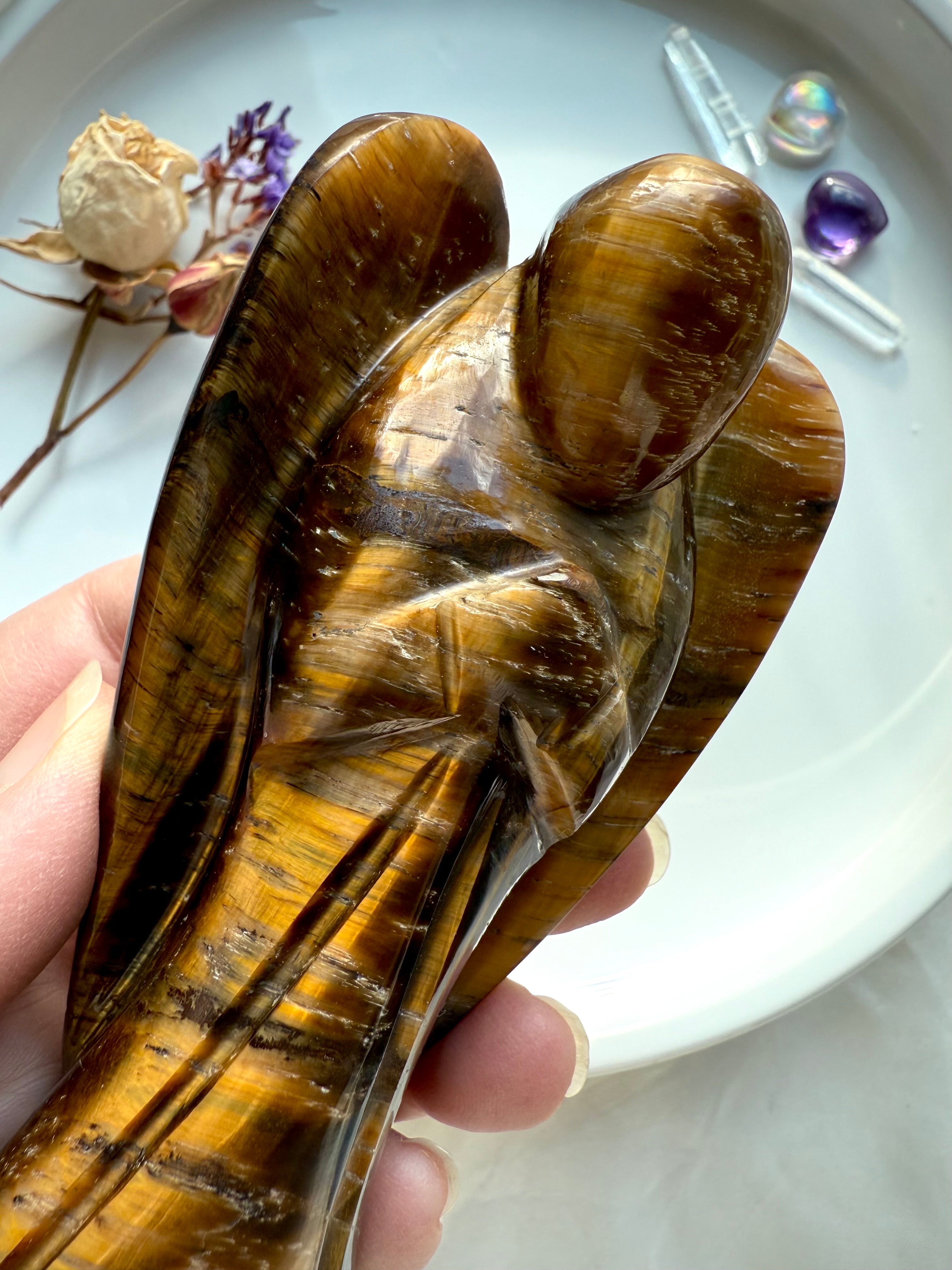 Close-up of polished Golden Tiger’s Eye angel highlighting the chatoyancy and detailed carving