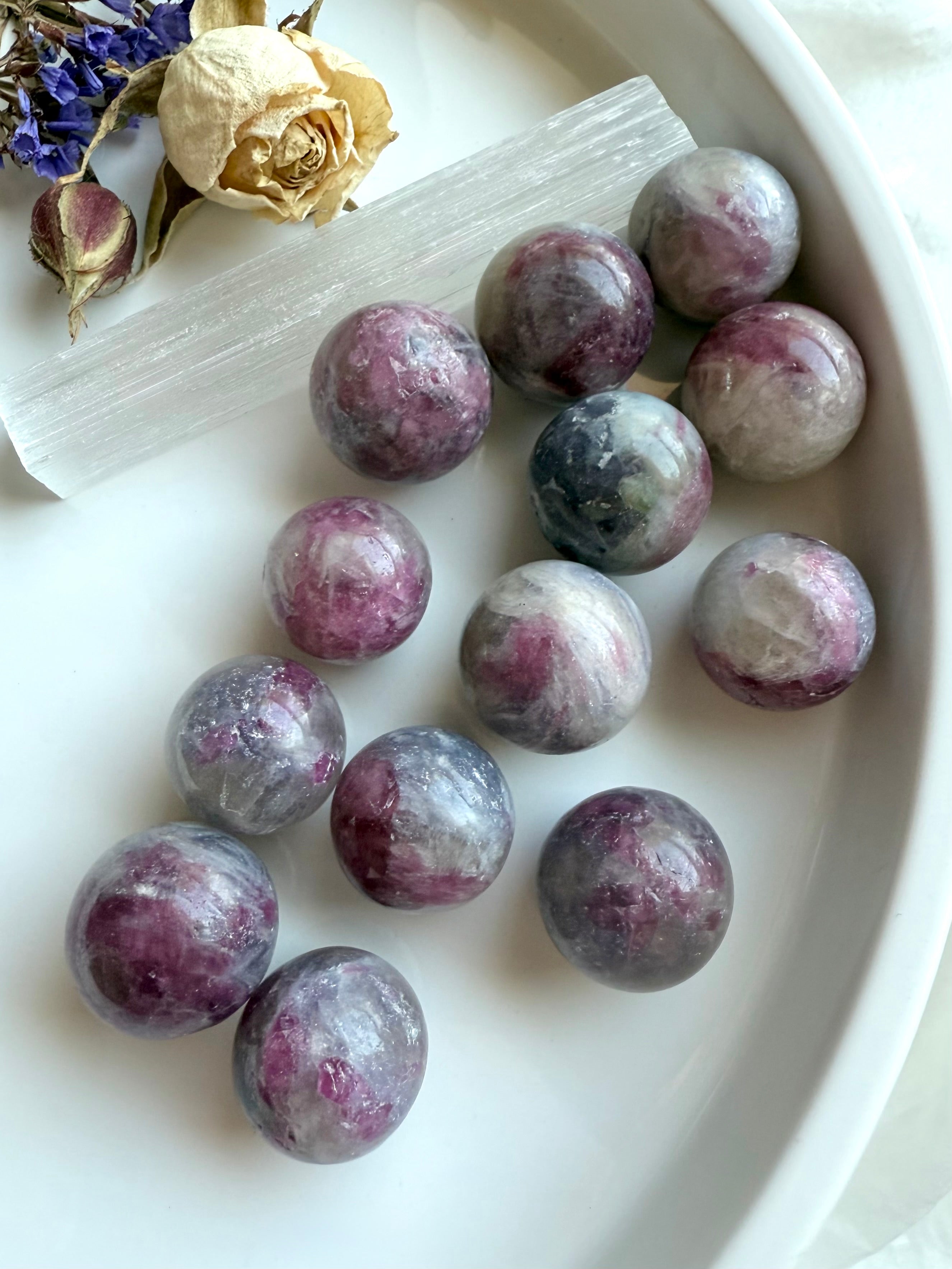 Unicorn Stone crystal spheres on a white plate, showing soothing patterns of pink and purple colors