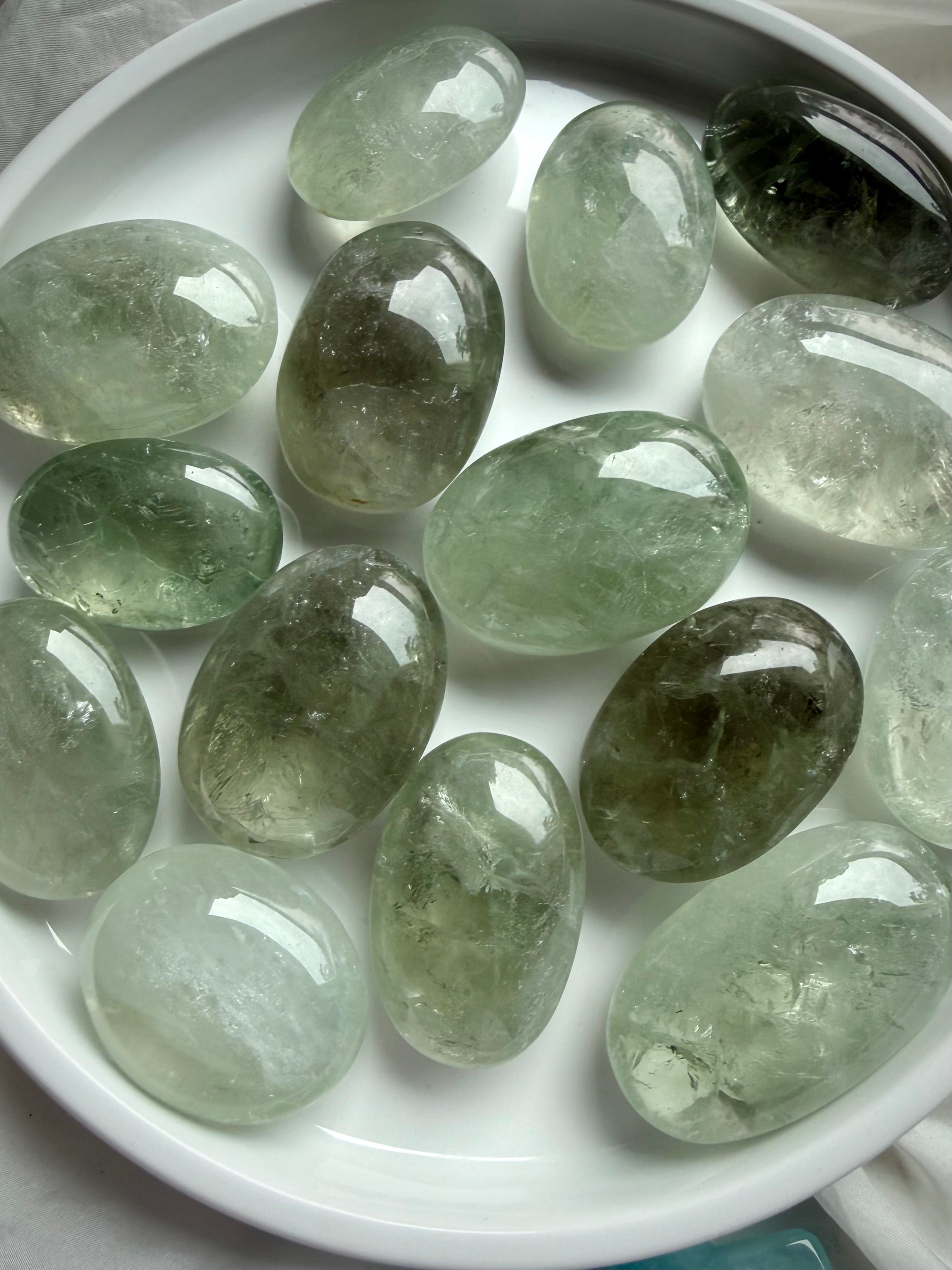 Assorted Prasiolite palm stones in bowl showing color variation and translucent green tones