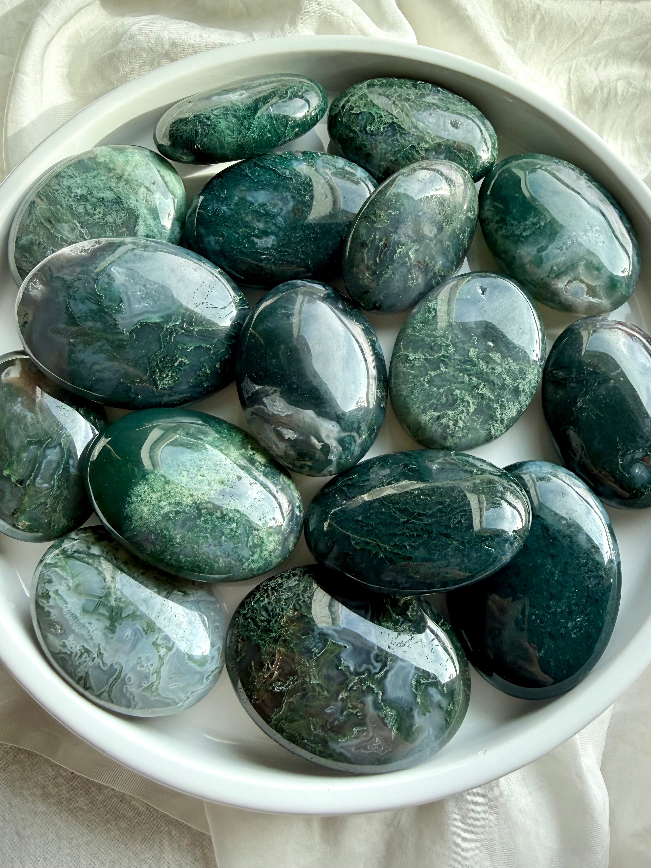 Polished moss agate palm stones showing natural green inclusions and earthy patterns, grounding crystals for stress relief