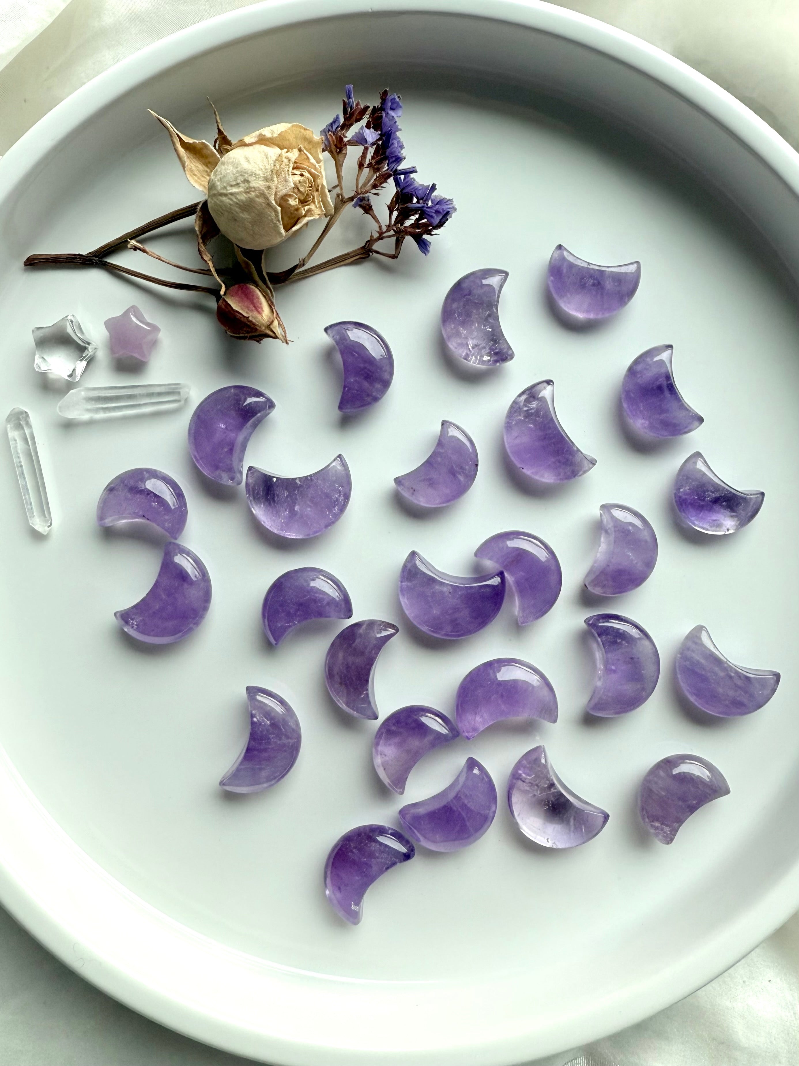 Small amethyst moon crystals scattered with crystal points and dried flowers