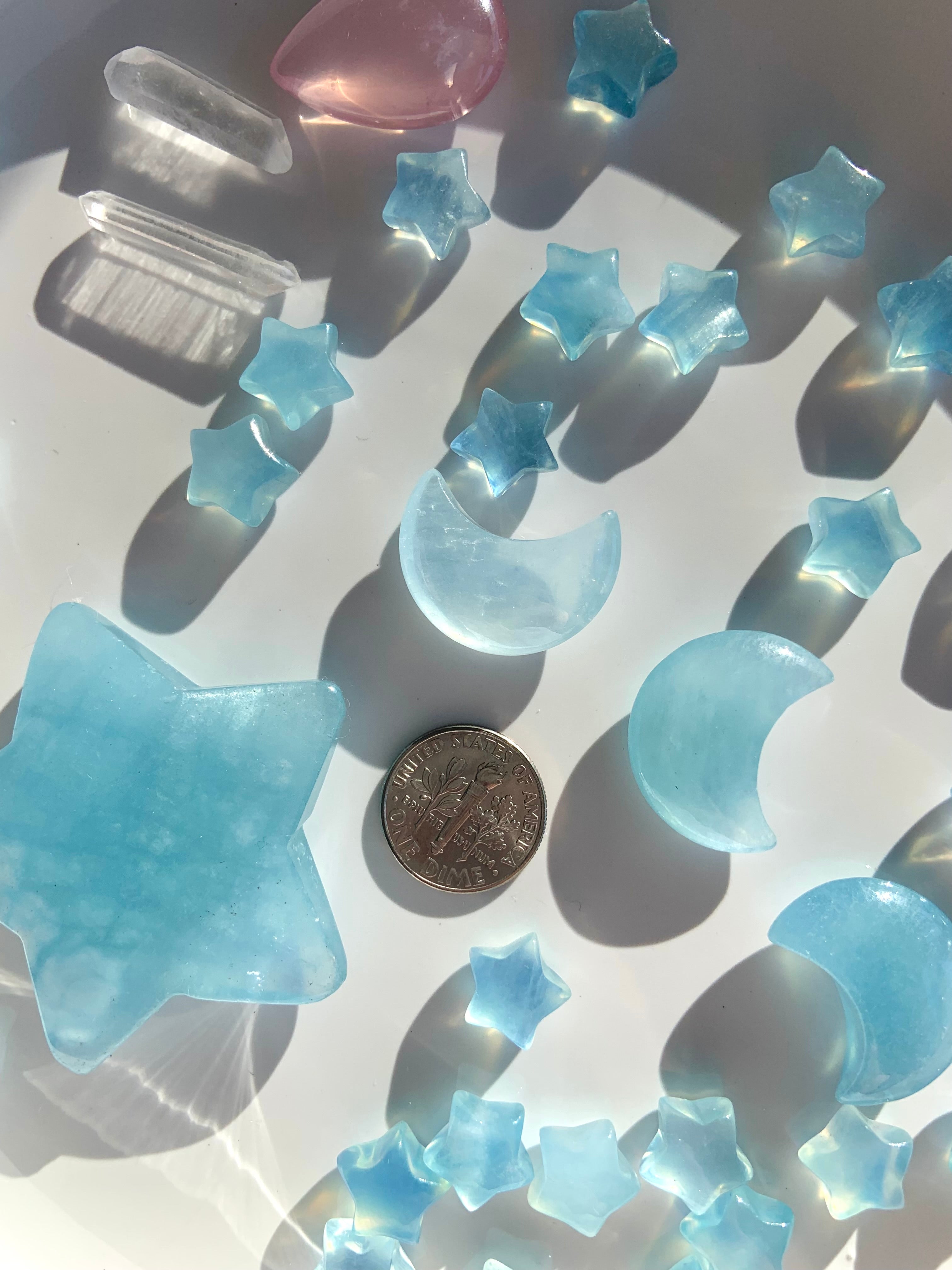 Aquamarine moons and stars next to a dime for scale