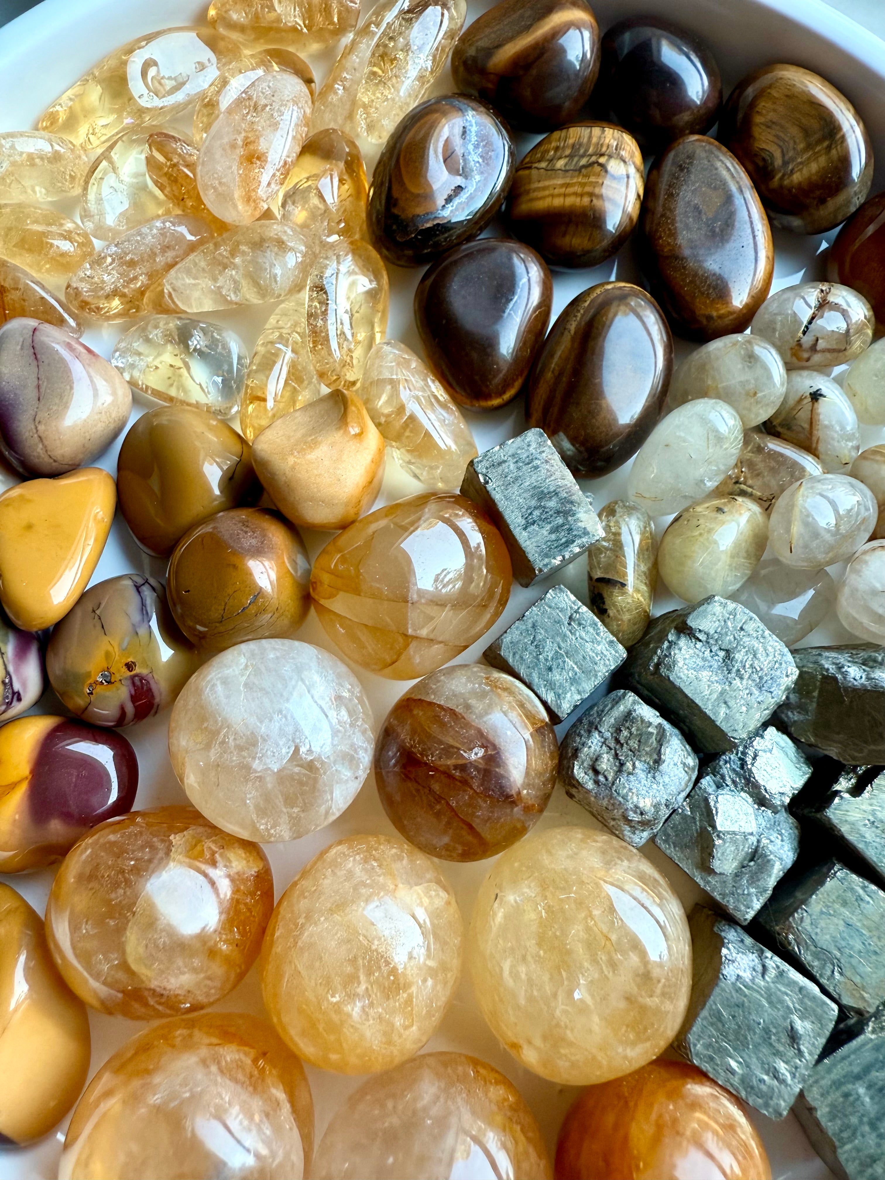 Close-up of segmented crystal pie layout — golden healer, citrine, golden rutile, tiger’s eye, yellow mookaite, and pyrite arranged in radiant abundance