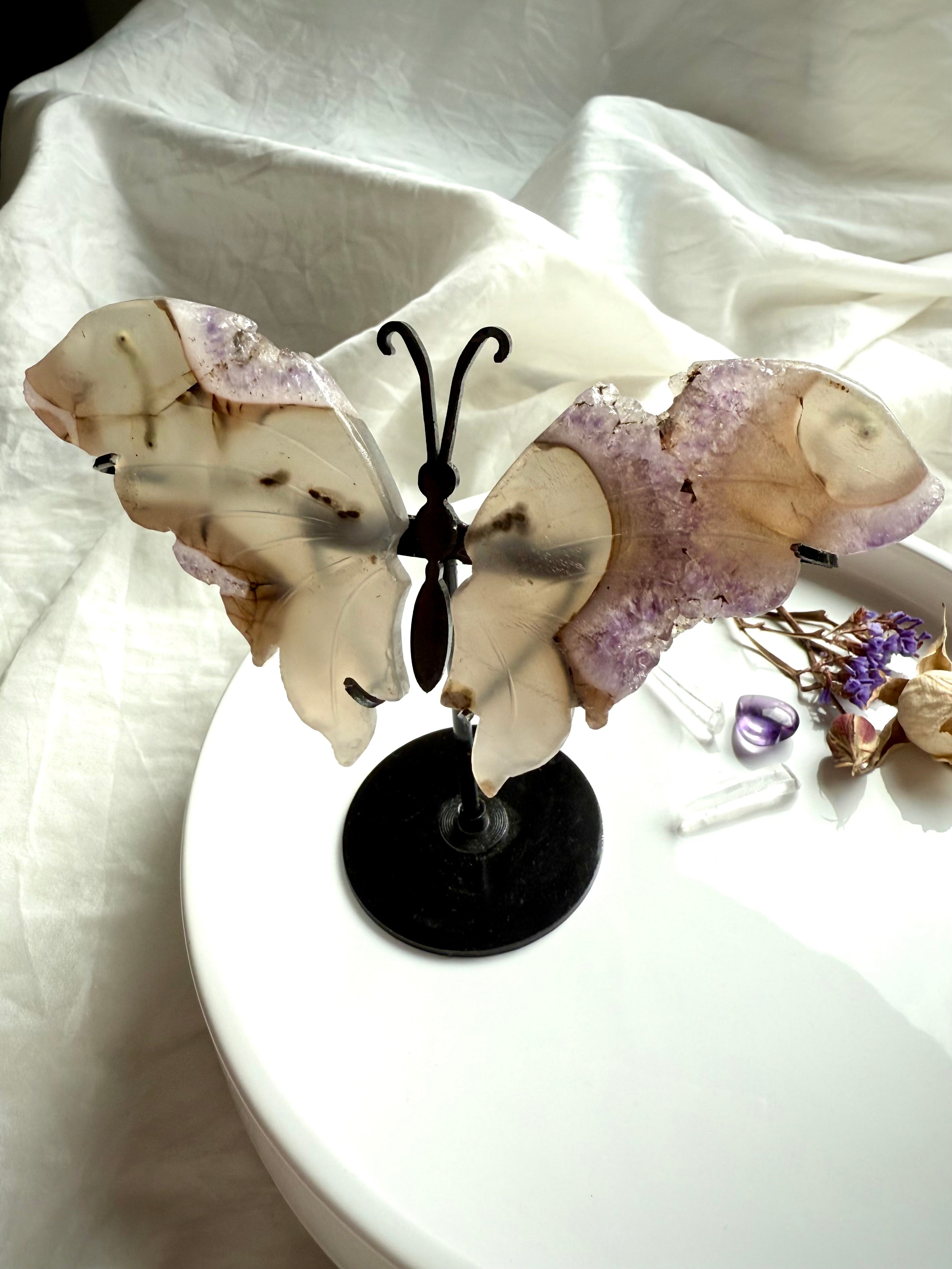 Druzy amethyst and agate butterfly wings displayed on black metal stand, sparkling lavender crystals and earthy agate banding.