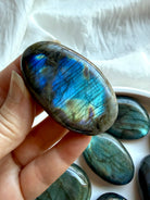 Labradorite palm stone held in hand with blue flash and shimmering iridescence