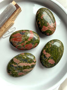 overhead Unakite palm stones on tray polished healing crystals for heart chakra love balance and grounding