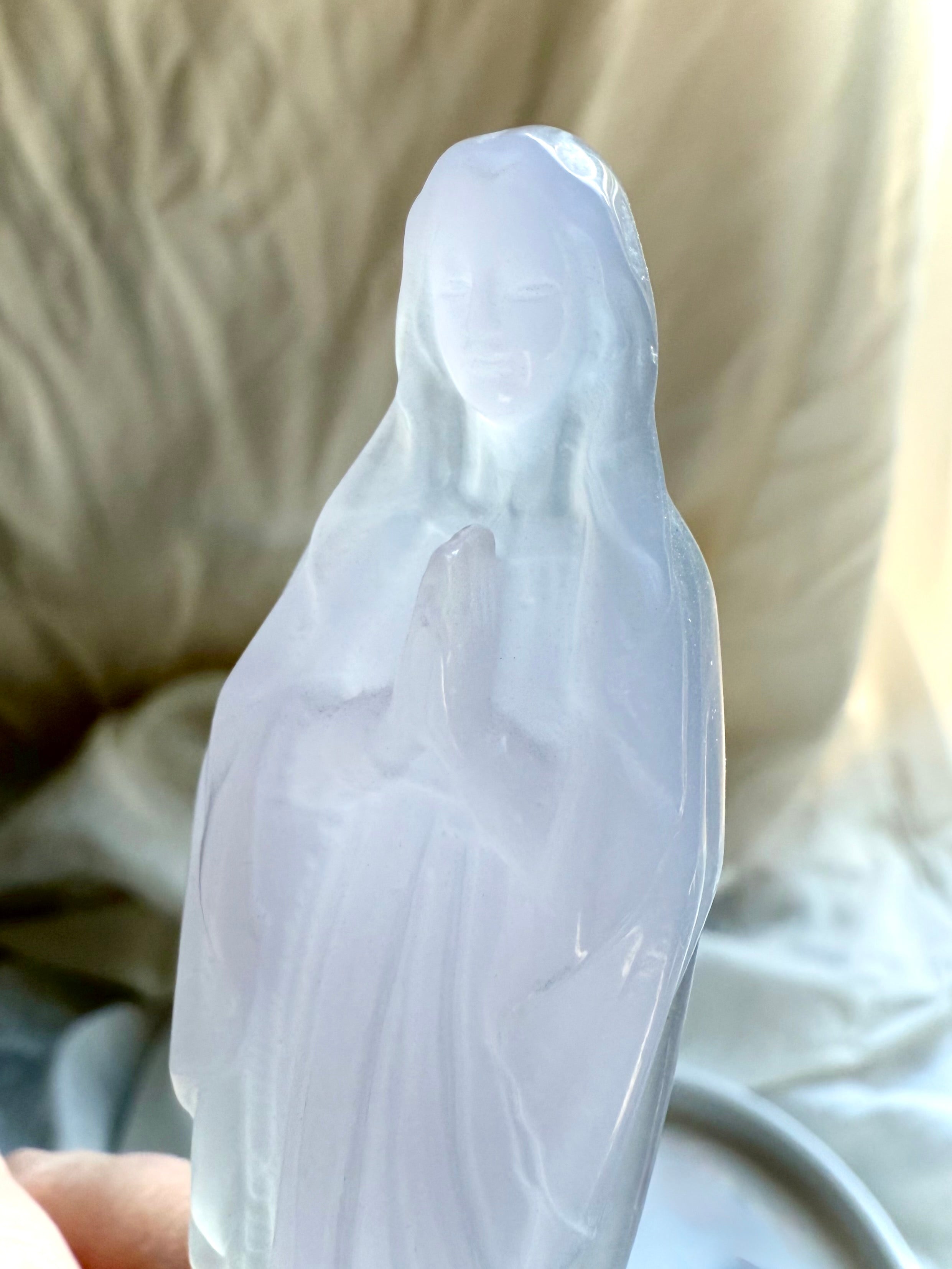 Mother Mary crystal carving held in hand, showing the soft translucent lavender and green coloring of Yttrium Fluorite