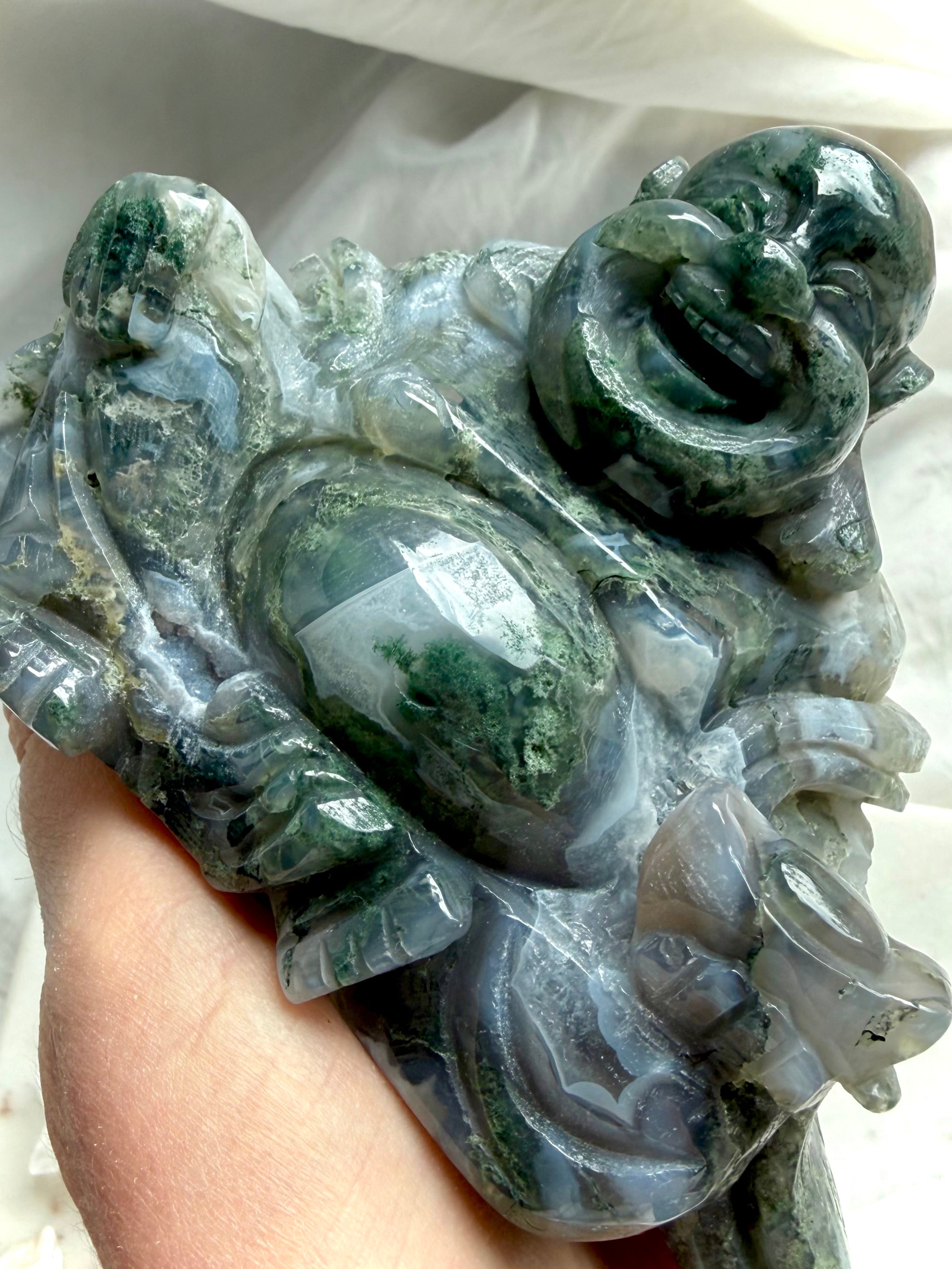 Close-up of a Large Moss Agate Laughing Buddha statue showcasing intricate carving, scenic Moss Agate, and glossy finish