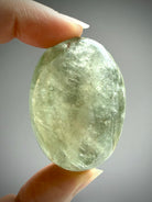 Translucent Prasiolite palm stone displaying natural inclusions and green amethyst glow