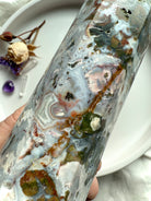 Macro detail of Cosmic Ocean Jasper crystal point with layered ocean-like patterns, mineral inclusions, and sparkling druzy texture