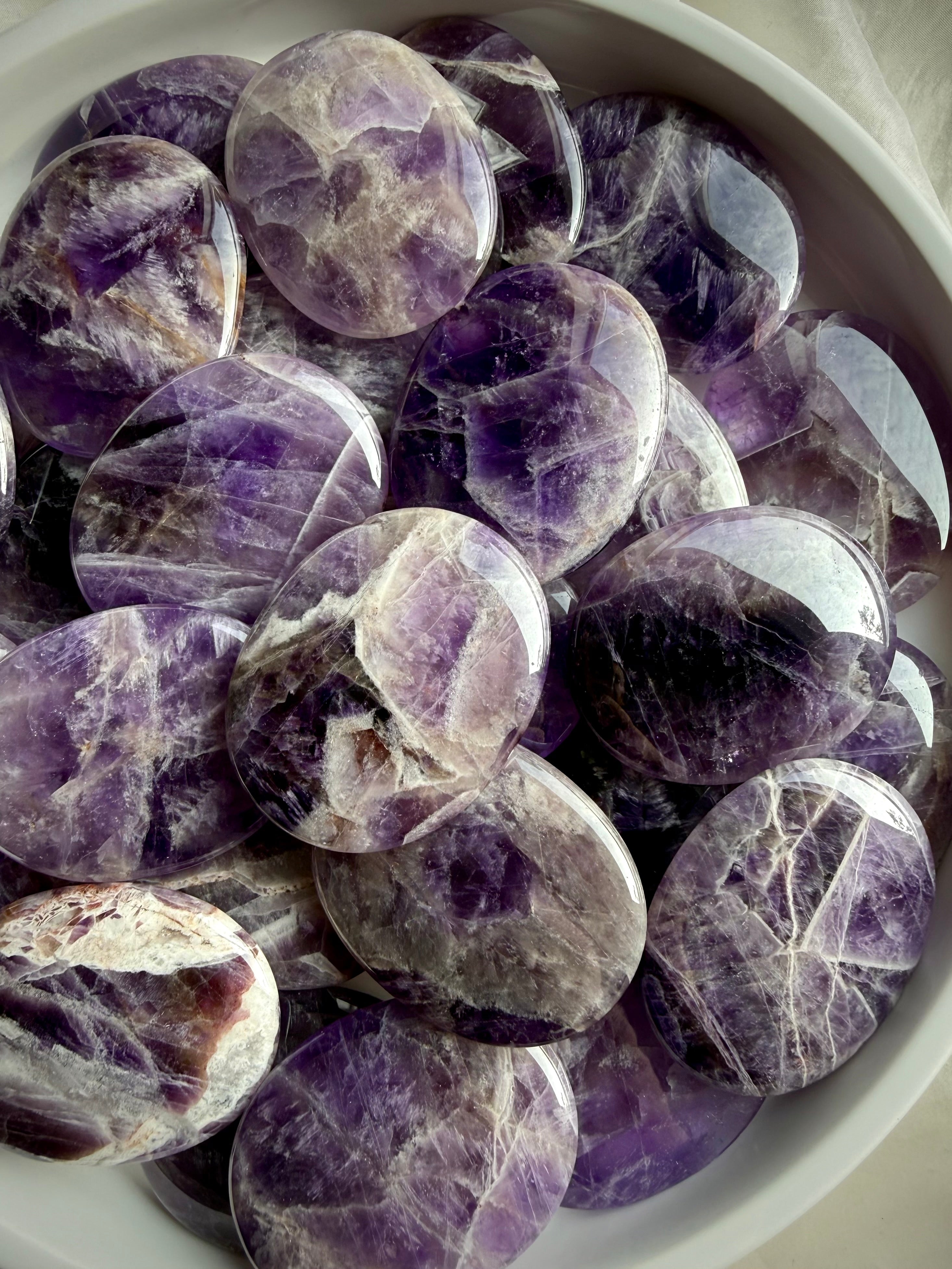 Dream amethyst flat palm stones showing natural variation in purple, lavender, white, and smoky banding, polished pocket crystals for calm and restful sleep