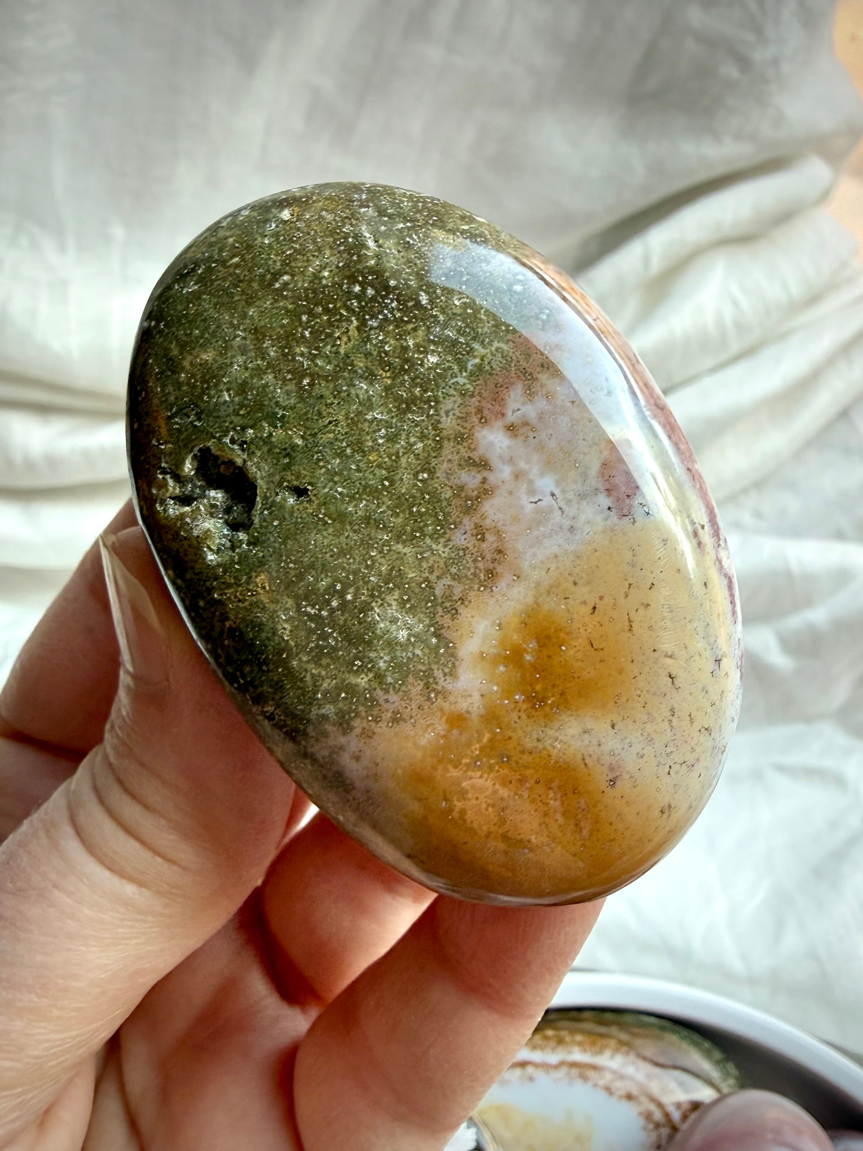 Polished Ocean Jasper palm stone with pink, mauve, cream, and earthy green coloring and natural landscape-like patterns