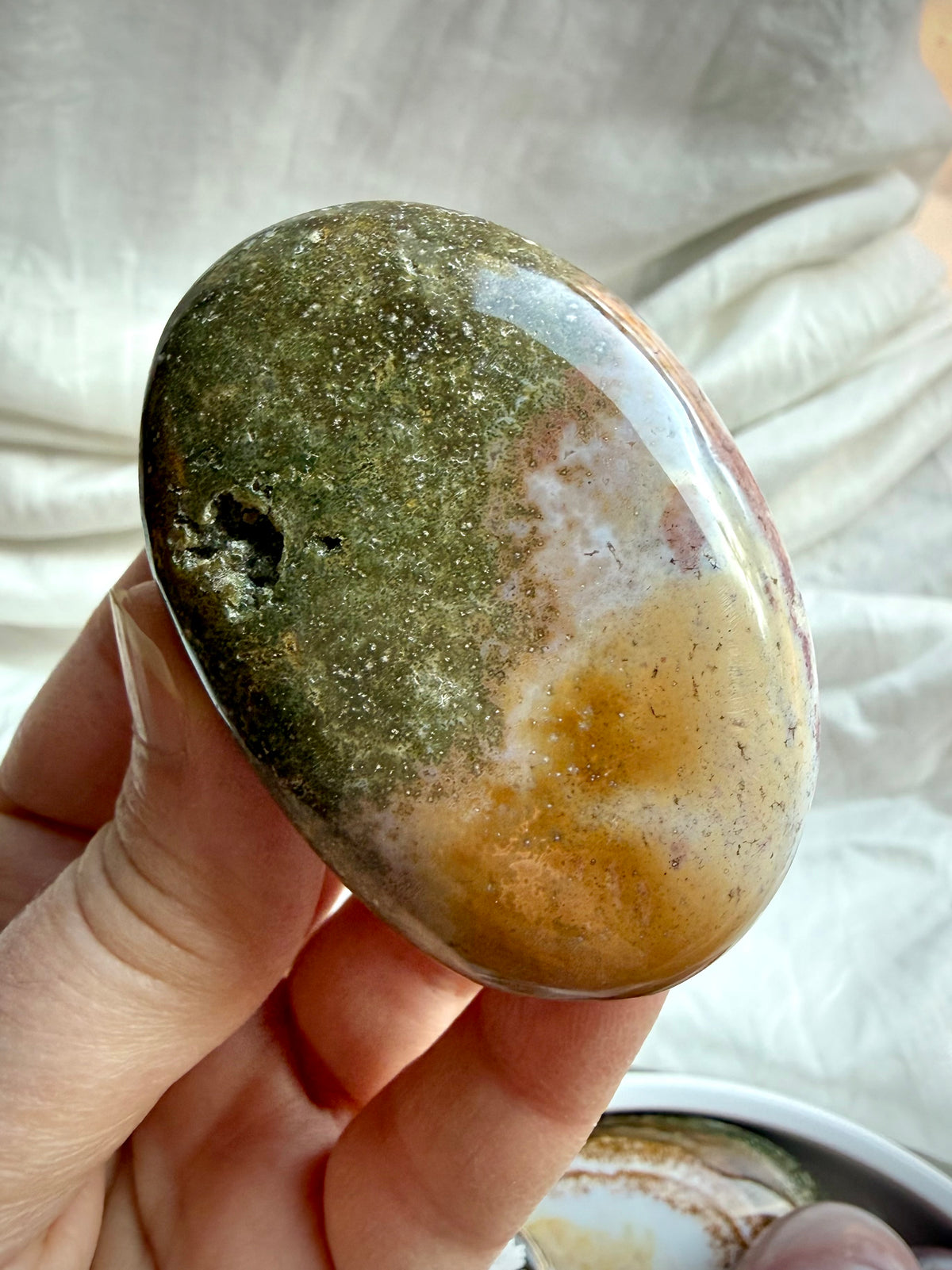Polished Ocean Jasper palm stone with pink, mauve, cream, and earthy green coloring and natural landscape-like patterns