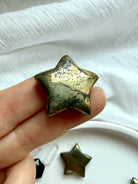 Close-up of polished Pyrite star carving with sparkling metallic texture and natural golden-bronze luster