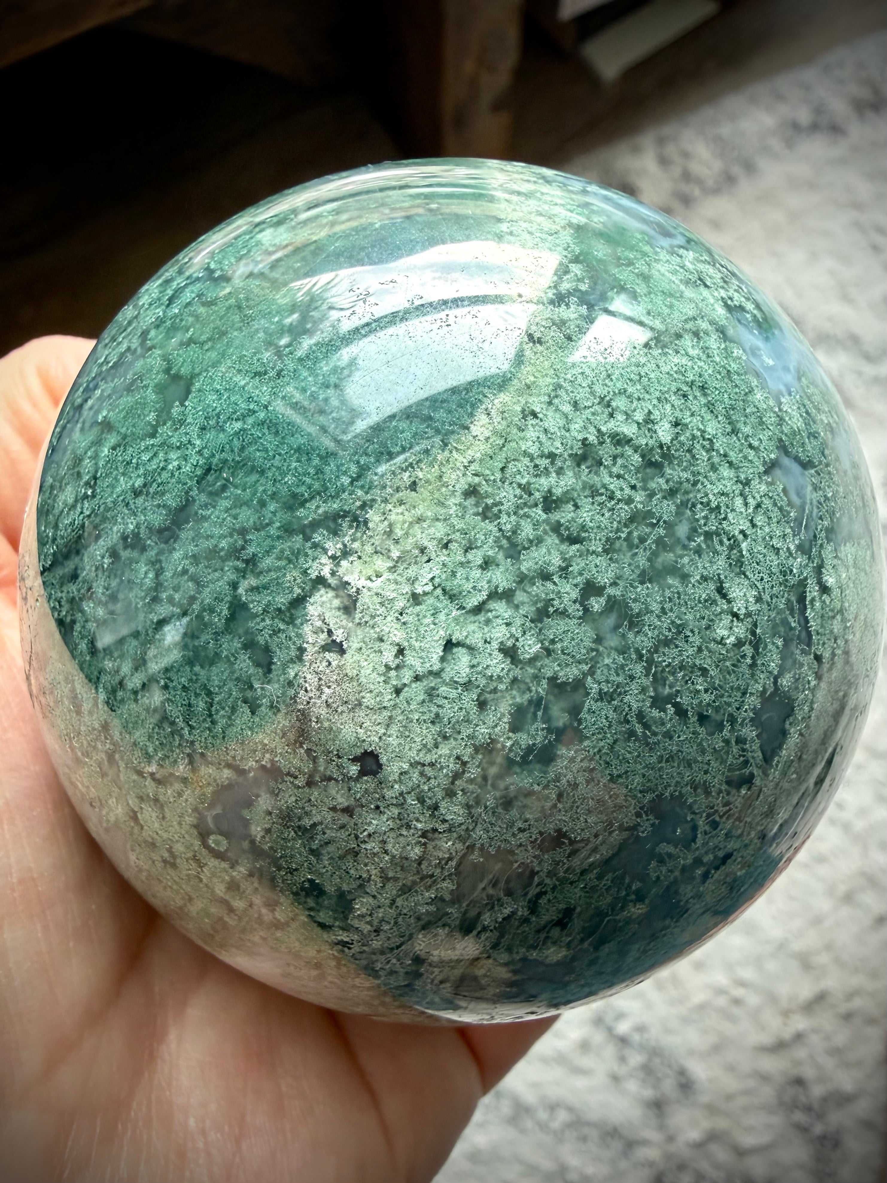 Polished Moss Agate sphere showing translucent areas, crystal formations, and forest-like inclusions