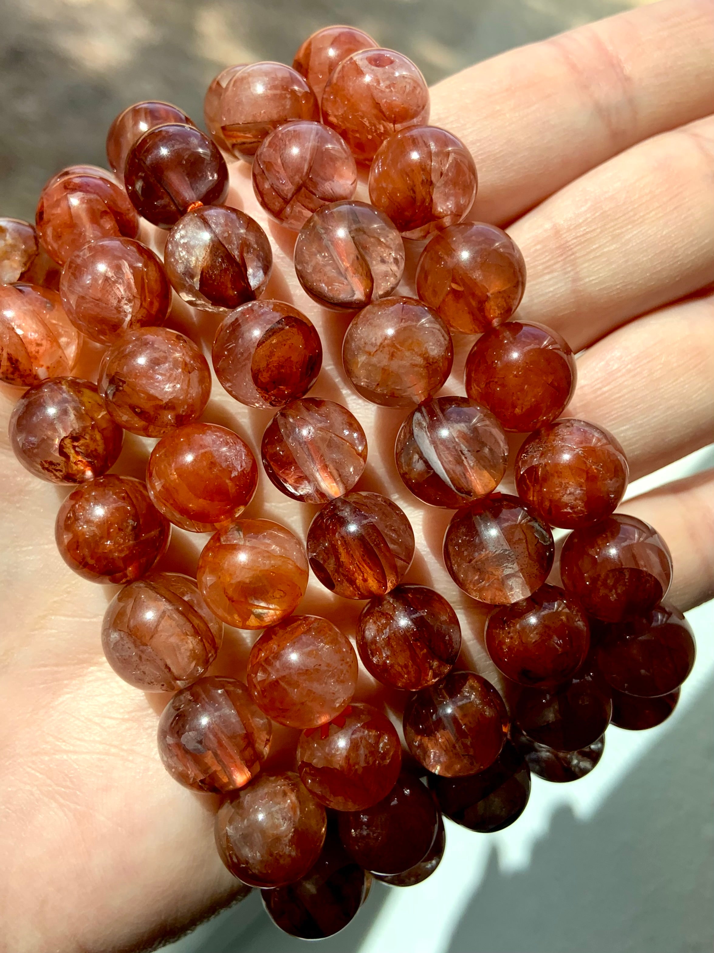 Close-up side view of several high-quality Fire Quartz bracelets, highlighting natural color patterns and glossy polished beads
