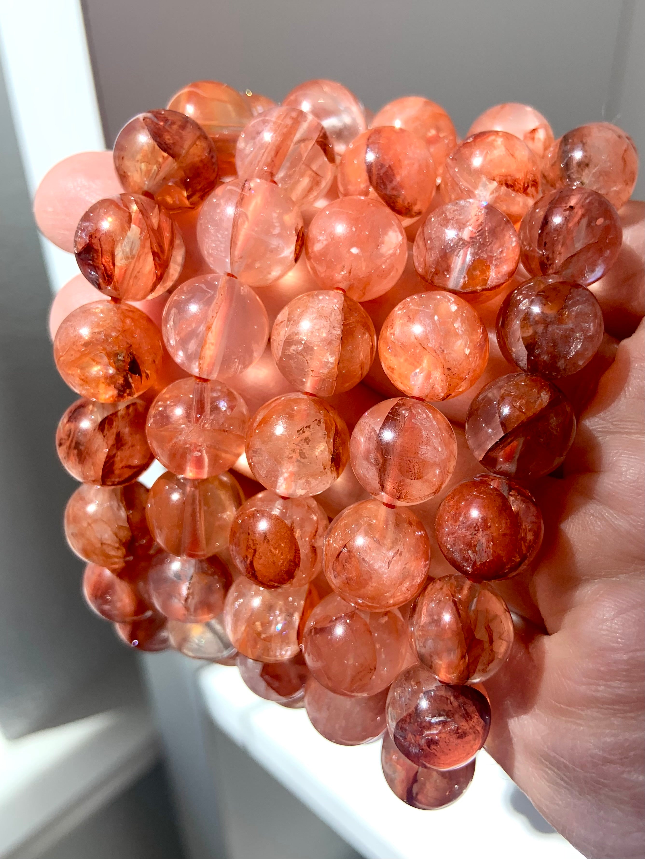 Side view of multiple Fire Quartz crystal bracelets, showcasing bead size, rich color, and natural inclusions