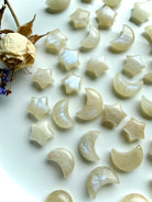 Moonstone moons and stars with celestial crystal carvings arranged on a white dish